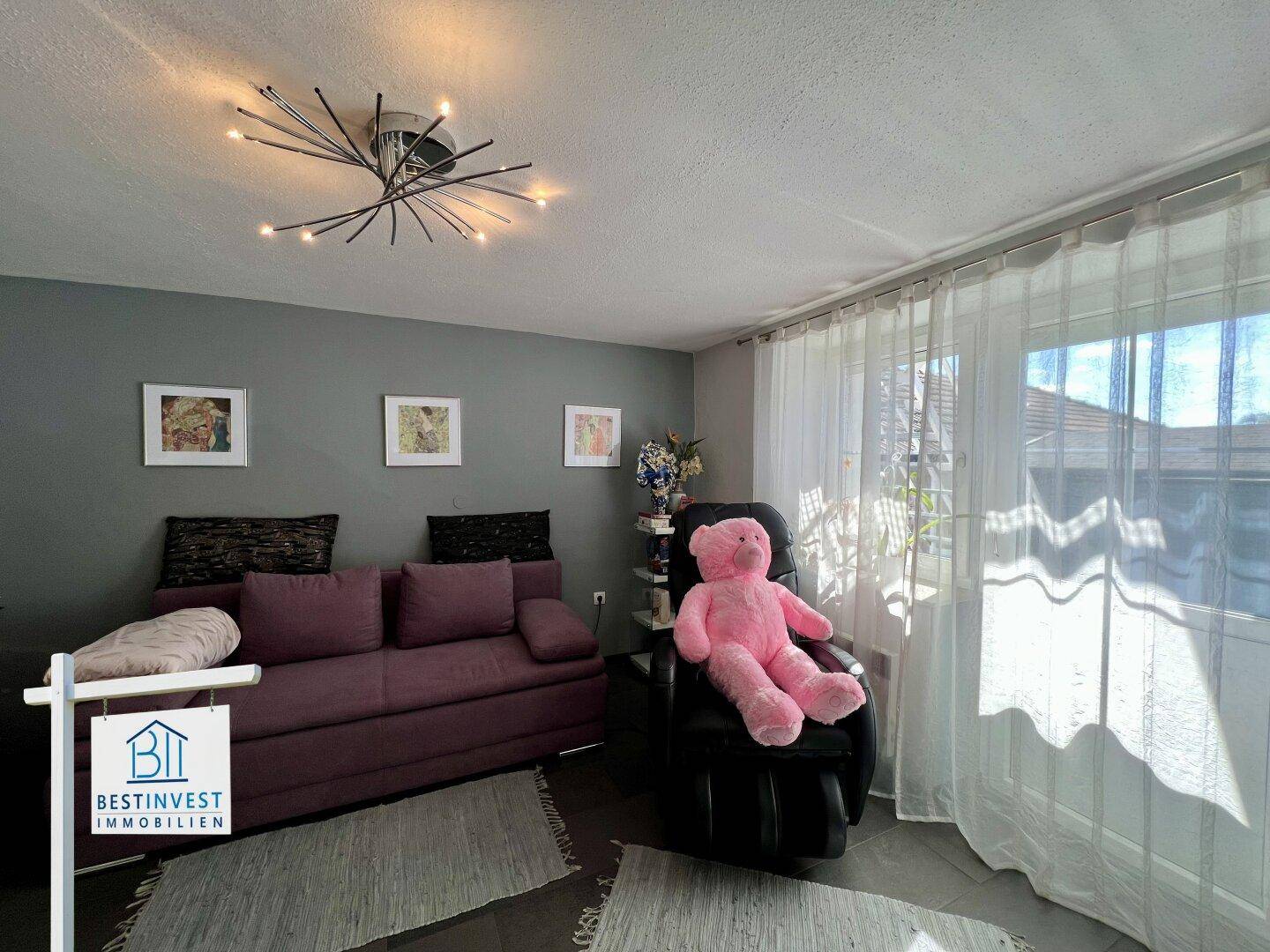 Gemütlicher Raum mit Sofa, großem Fenster und viel Tageslicht.