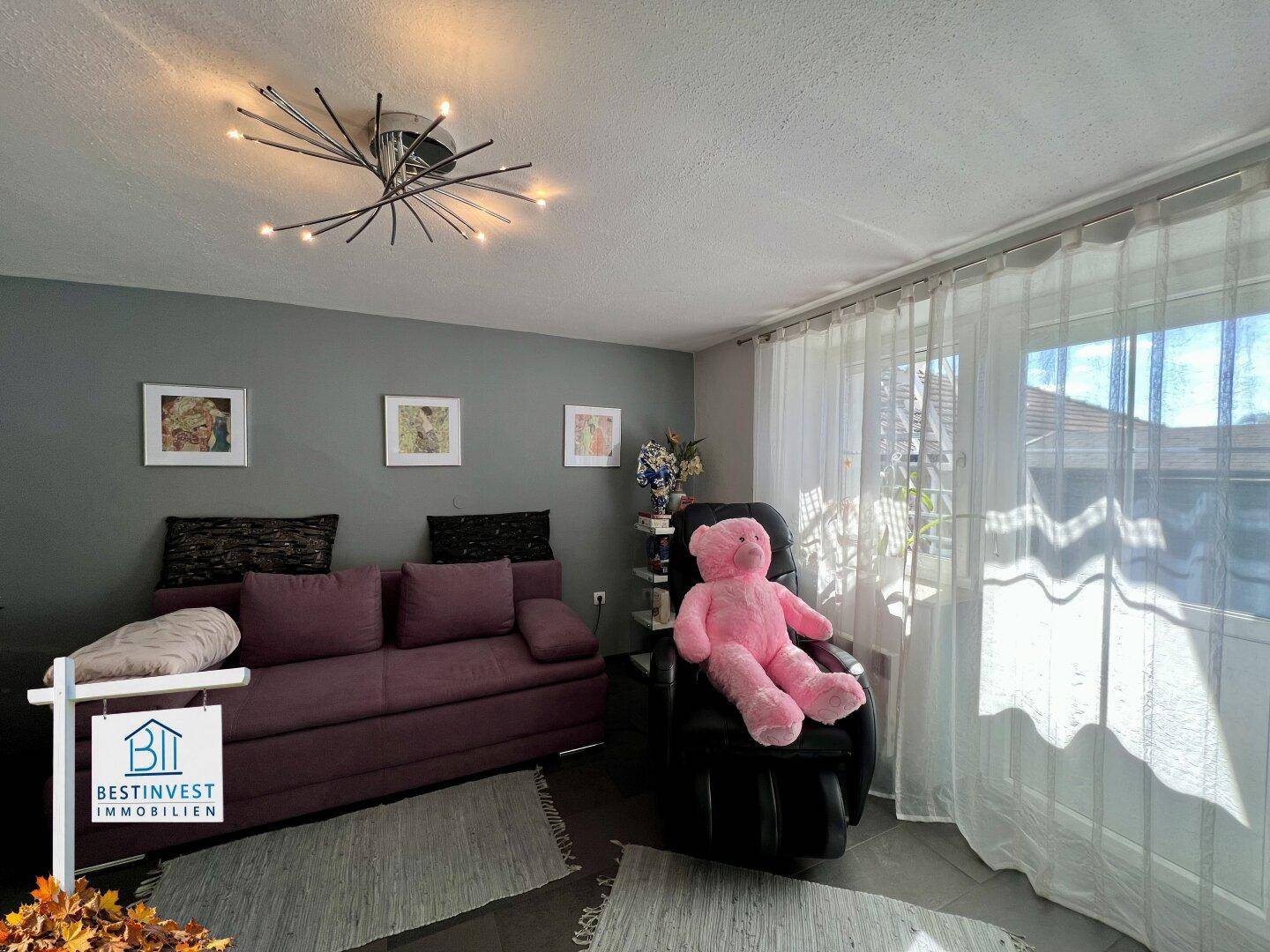 Gemütliches Schlafzimmer mit Sofa, großem Fenster und moderner Deckenleuchte, hell und komfortabel.