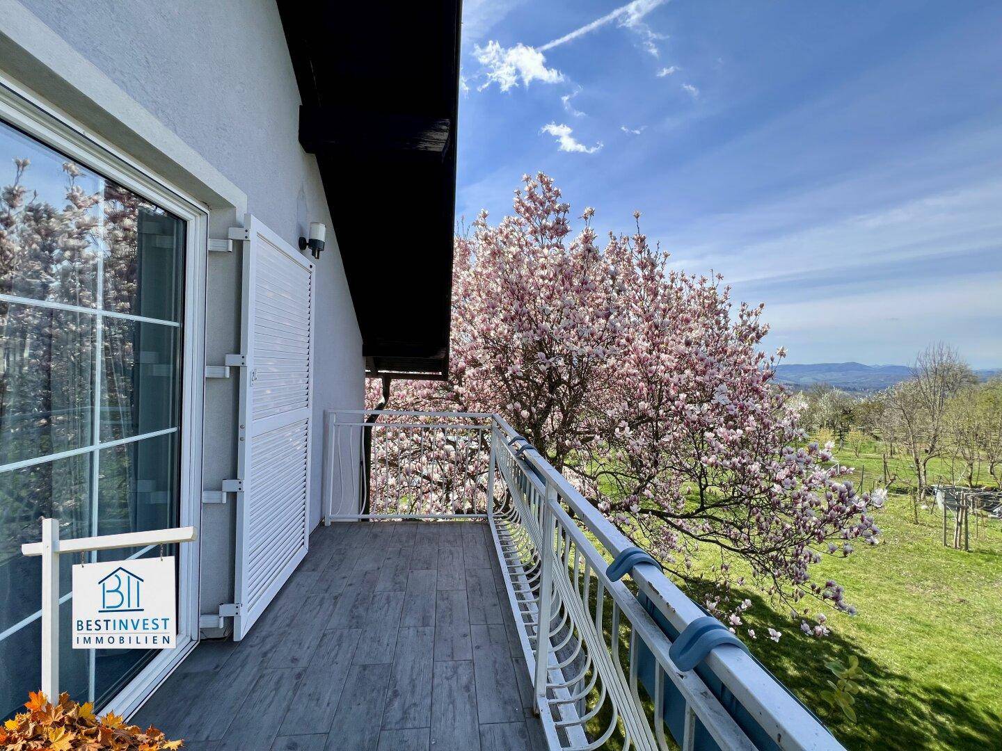 Balkon mit malerischem Blick auf blühende Bäume und die umliegende Landschaft.