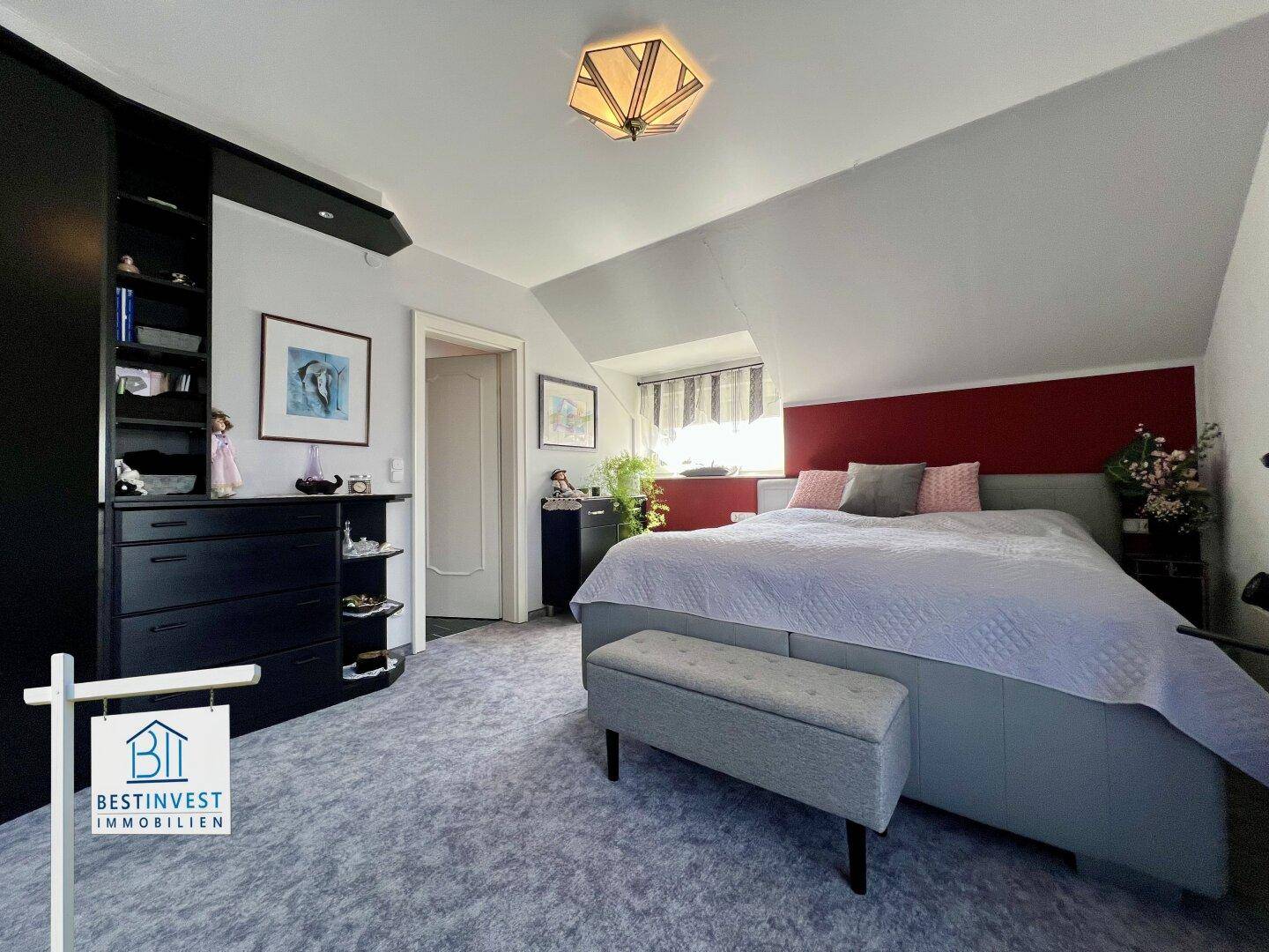 Schlafzimmer mit Doppelbett, Dachschräge und Teppichboden.