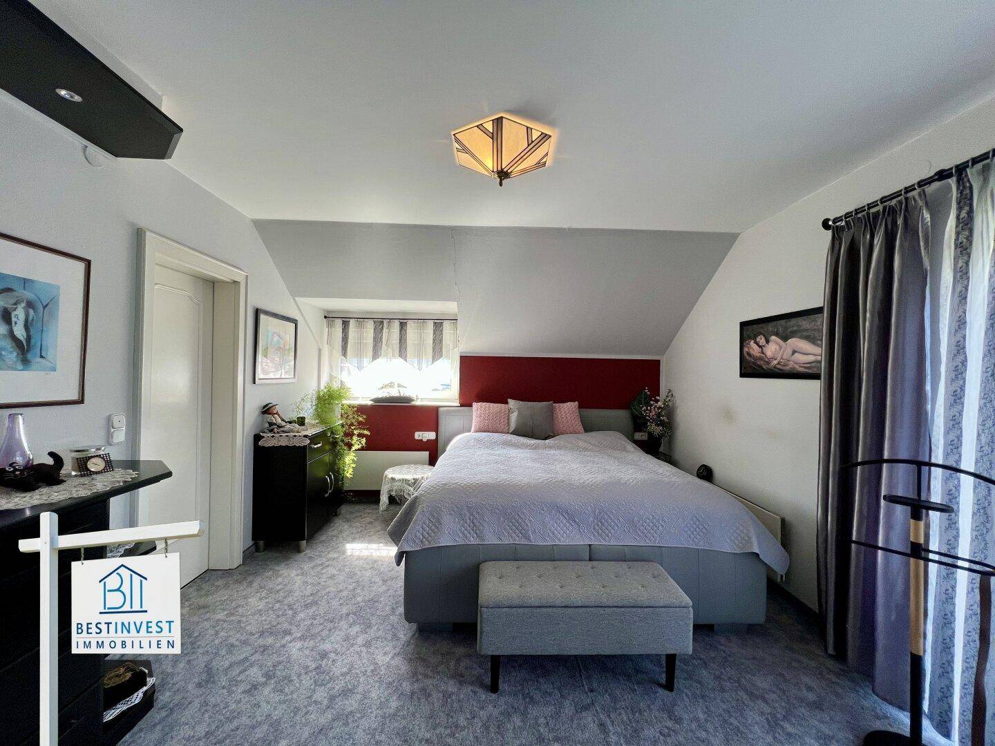 Helles Schlafzimmer mit großem Bett, Dachschräge und Fenster.