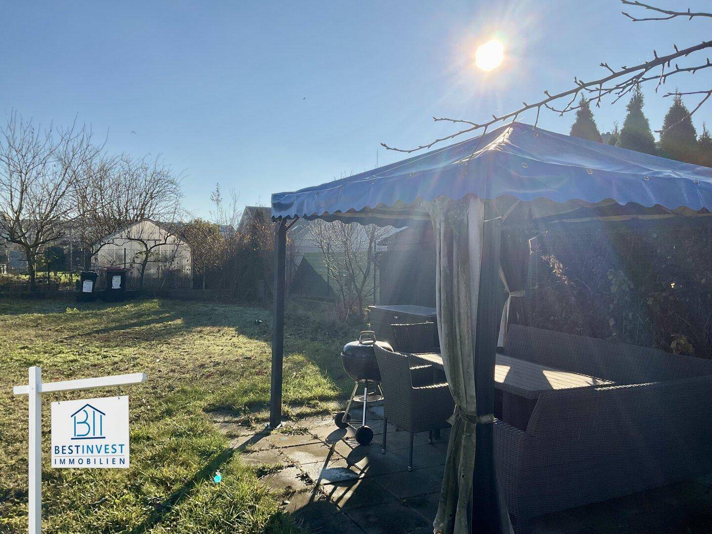 Sonnige Gartenterrasse mit Pavillon, Grill und viel Grünfläche für Entspannung.