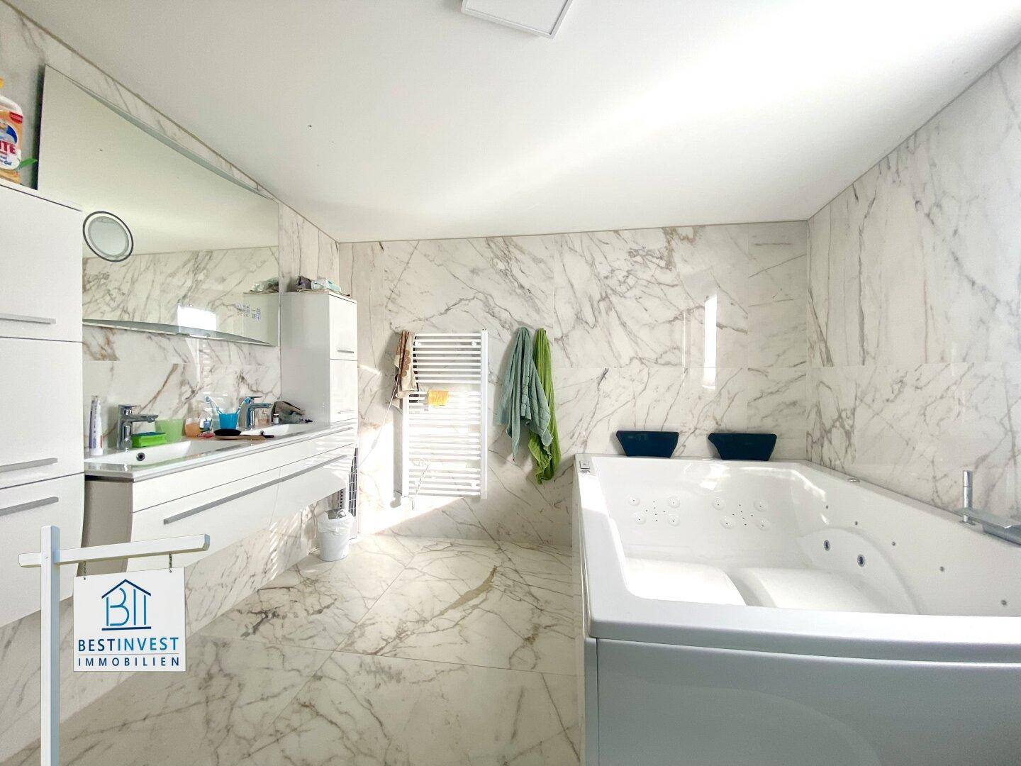 Luxuriöses Badezimmer mit Marmorfliesen, Whirlpool und modernem Doppelwaschbecken.