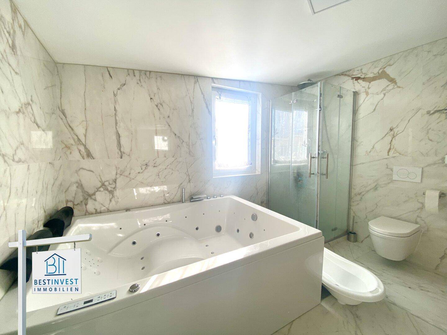 Elegantes Badezimmer mit Marmorfliesen, Whirlpool, Dusche und Fenster.