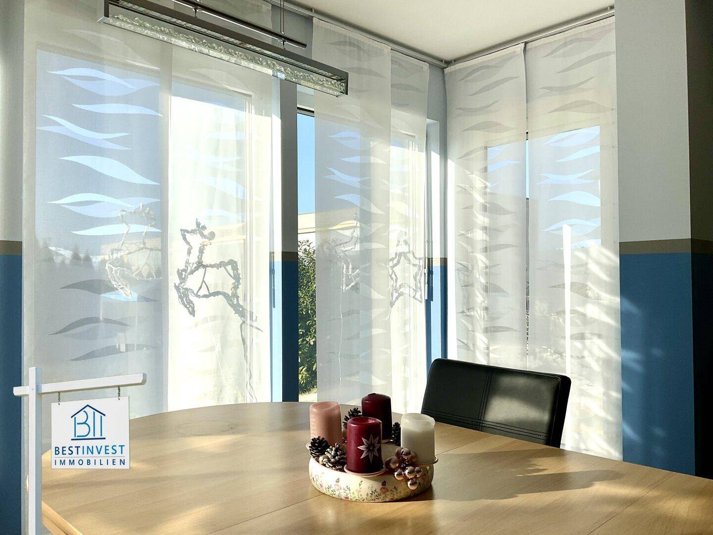 Detailansicht des Essbereichs mit Holztisch und dekorativen Fensterrollos.