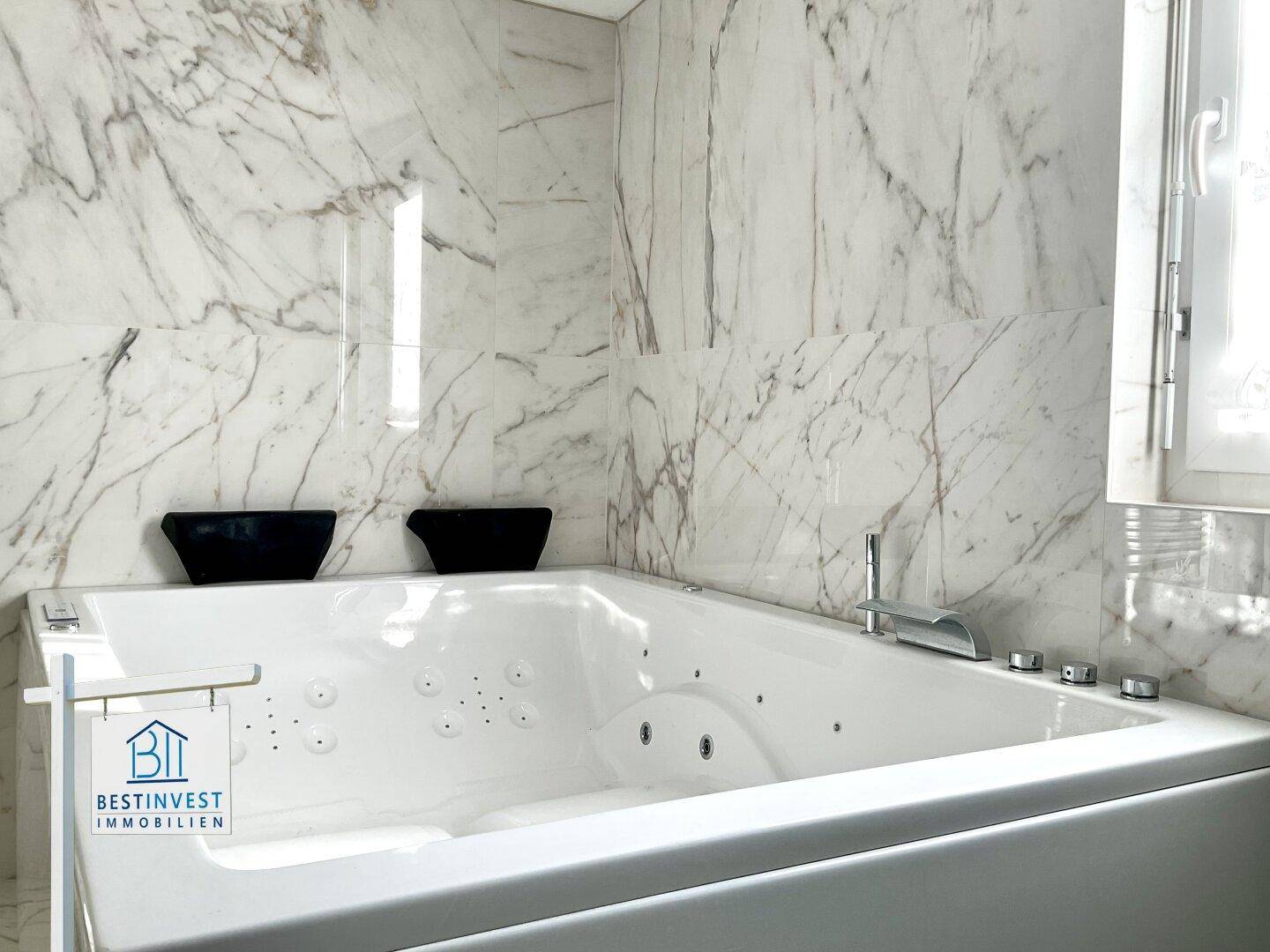 Luxuriöse Badewanne mit Whirlpool-Funktion in einem eleganten Badezimmer mit Marmorfliesen.