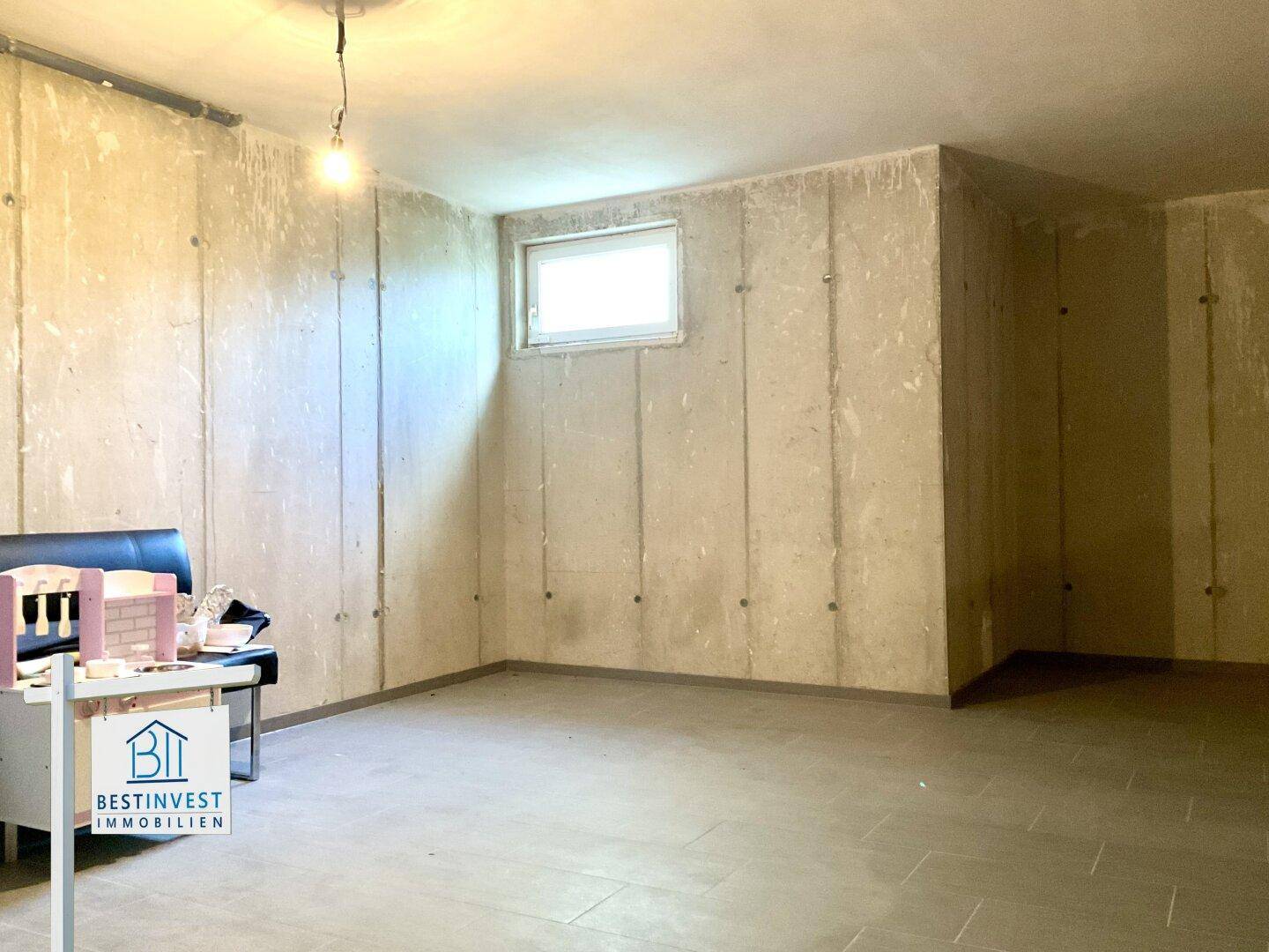 Unausgebauter Kellerraum mit Betonwänden und einem kleinen Fenster, ideal als Lagerfläche.