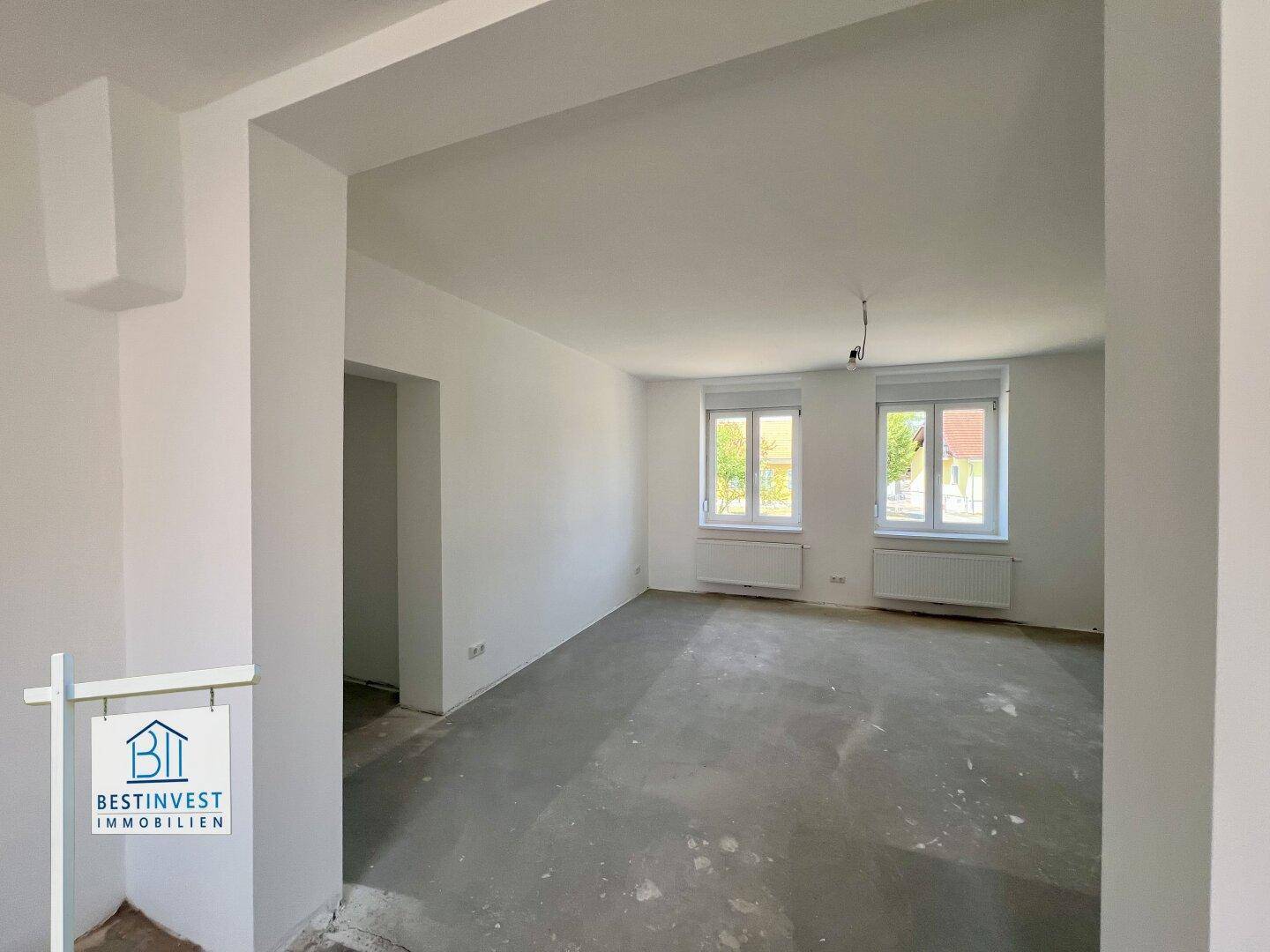 Helles Zimmer im Rohbauzustand mit zwei Fenstern und weiß gestrichenen Wänden, bereit für die Gestaltung.