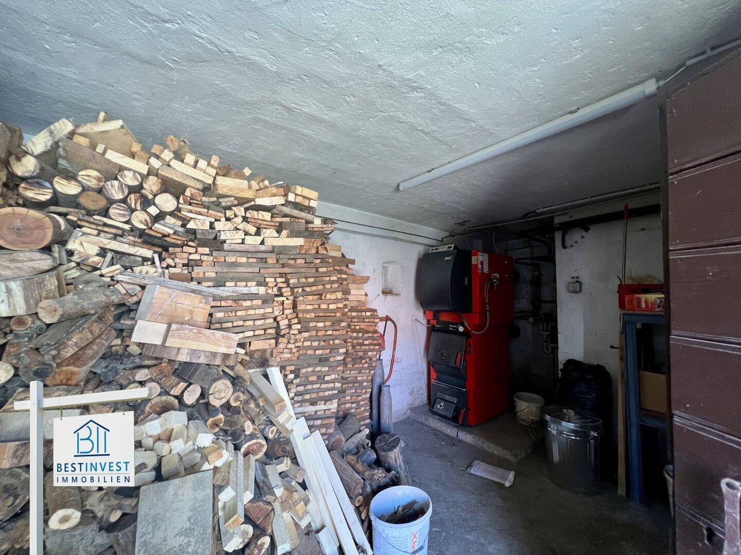 Heizraum mit Holzstapeln und einem modernen Heizkessel, bereit für den Winterbetrieb.