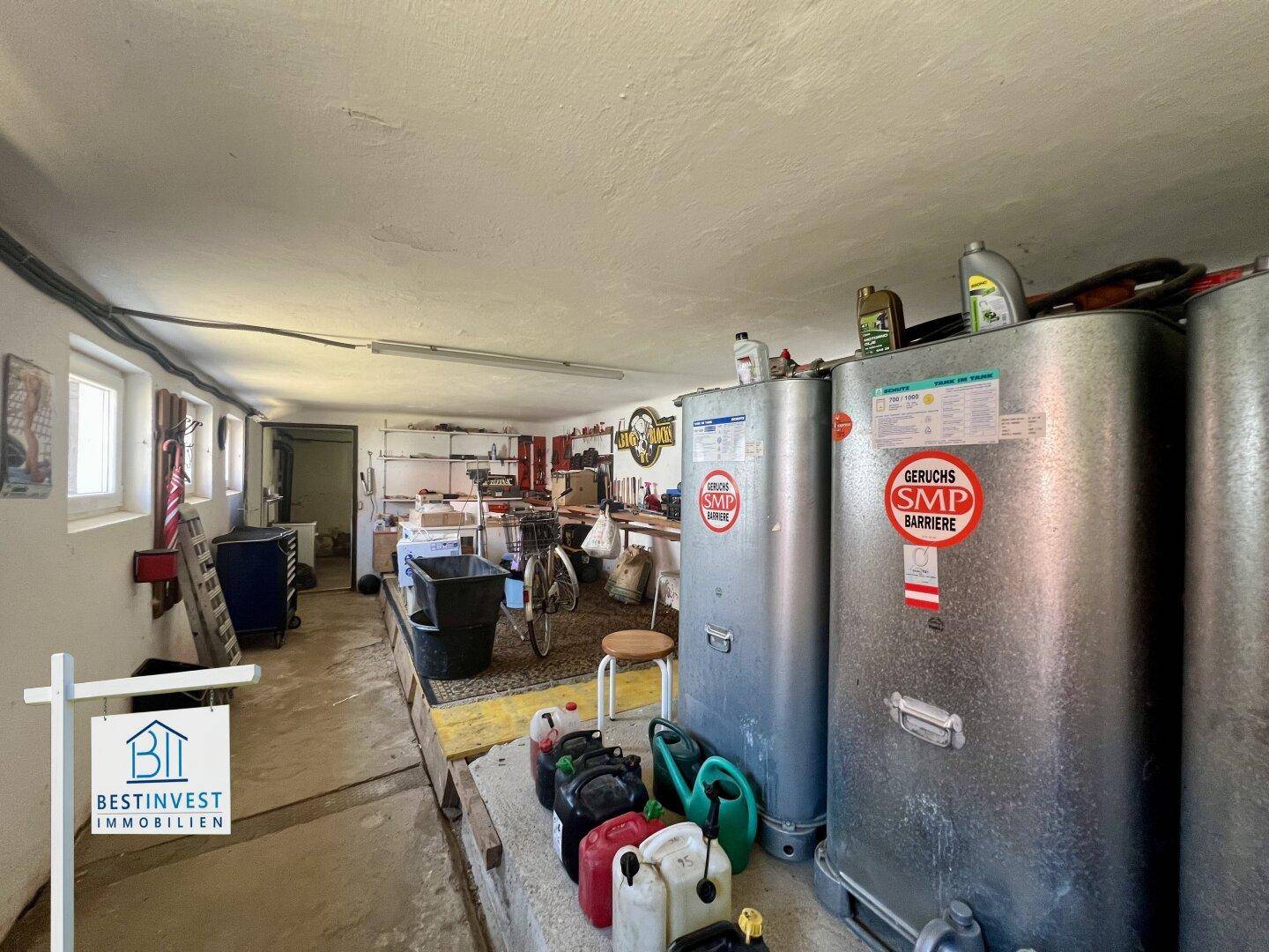 Geräumiger Werkstatt- oder Lagerraum mit Heizöltanks und verschiedenen Arbeitsmaterialien.