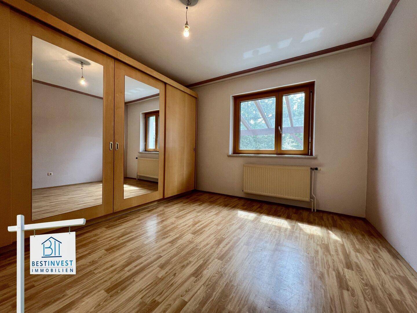 Helles Schlafzimmer mit Laminatboden und großem Spiegelschrank, bereit zur Einrichtung.