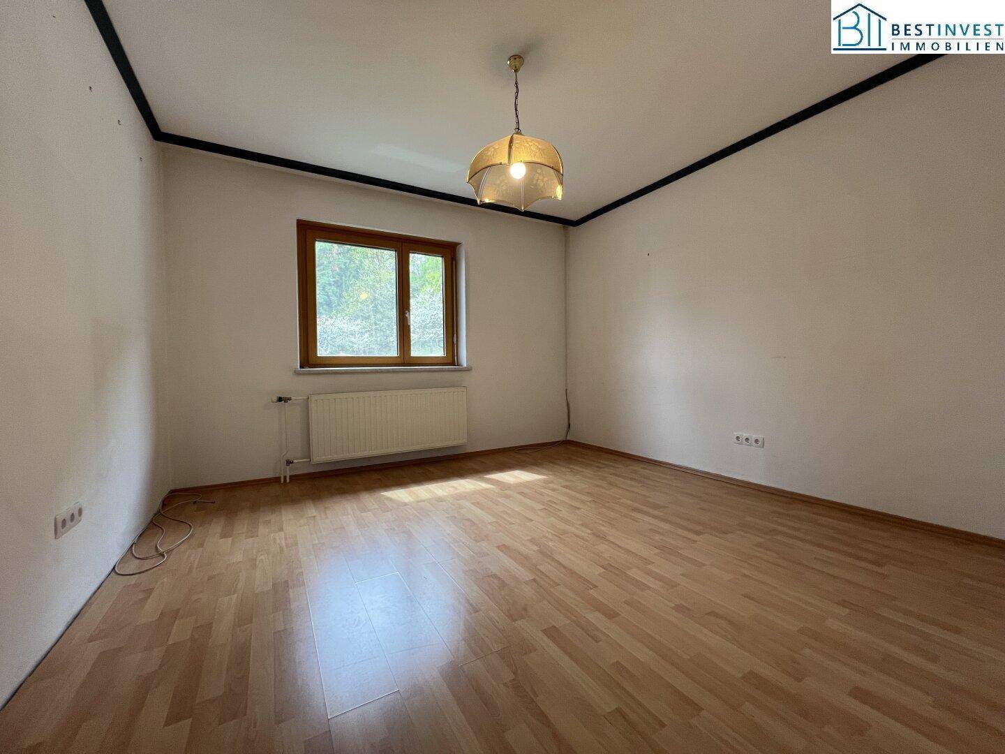 Geräumiges Zimmer mit Laminatboden und großem Fenster, bietet vielseitige Nutzungsmöglichkeiten.