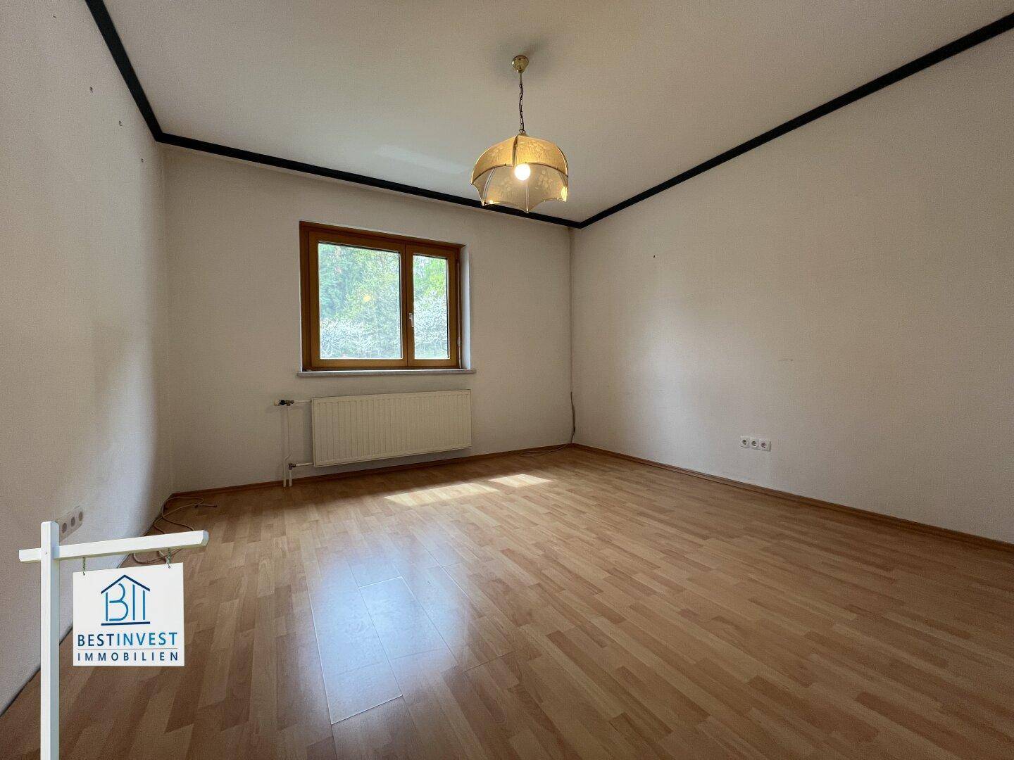 Geräumiges Zimmer mit Laminatboden und Fenster, ideal als Schlaf- oder Arbeitszimmer.