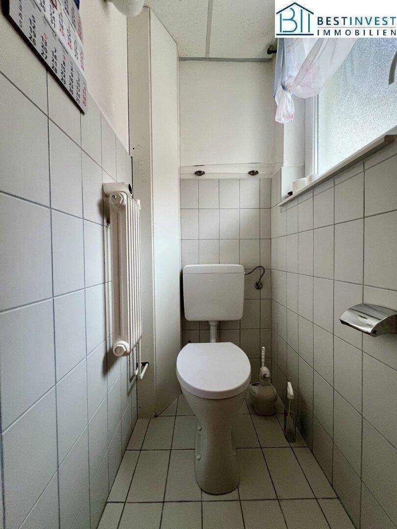 Kleines Gäste-WC mit weißen Fliesen und Fenster, funktional und hell gestaltet.