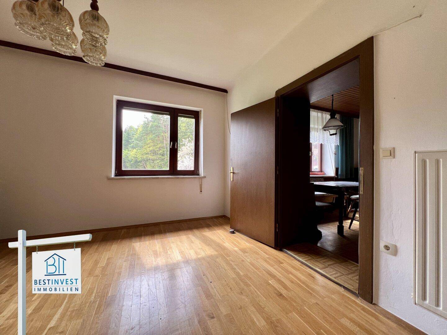 Helles Zimmer mit Holzboden und Fenster, bietet vielseitige Nutzungsmöglichkeiten.