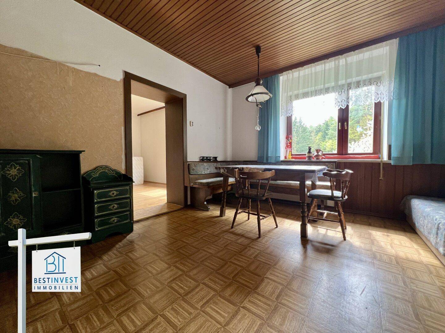 Traditioneller Essbereich mit Holztisch, Sitzbank und gemustertem Bodenbelag.