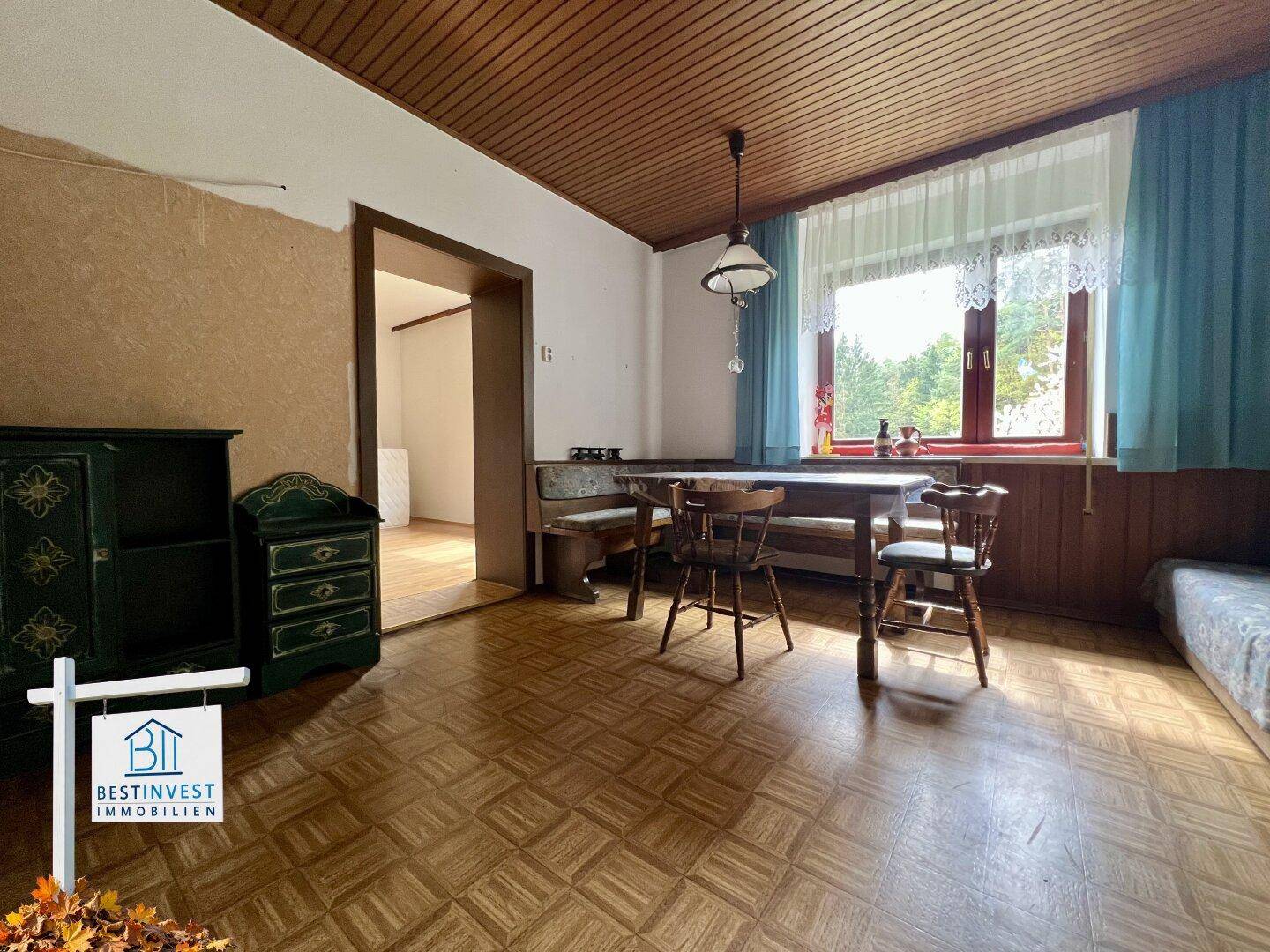 Gemütlicher Essbereich mit traditionellen Holzmöbeln und einem Fenster mit Vorhängen.