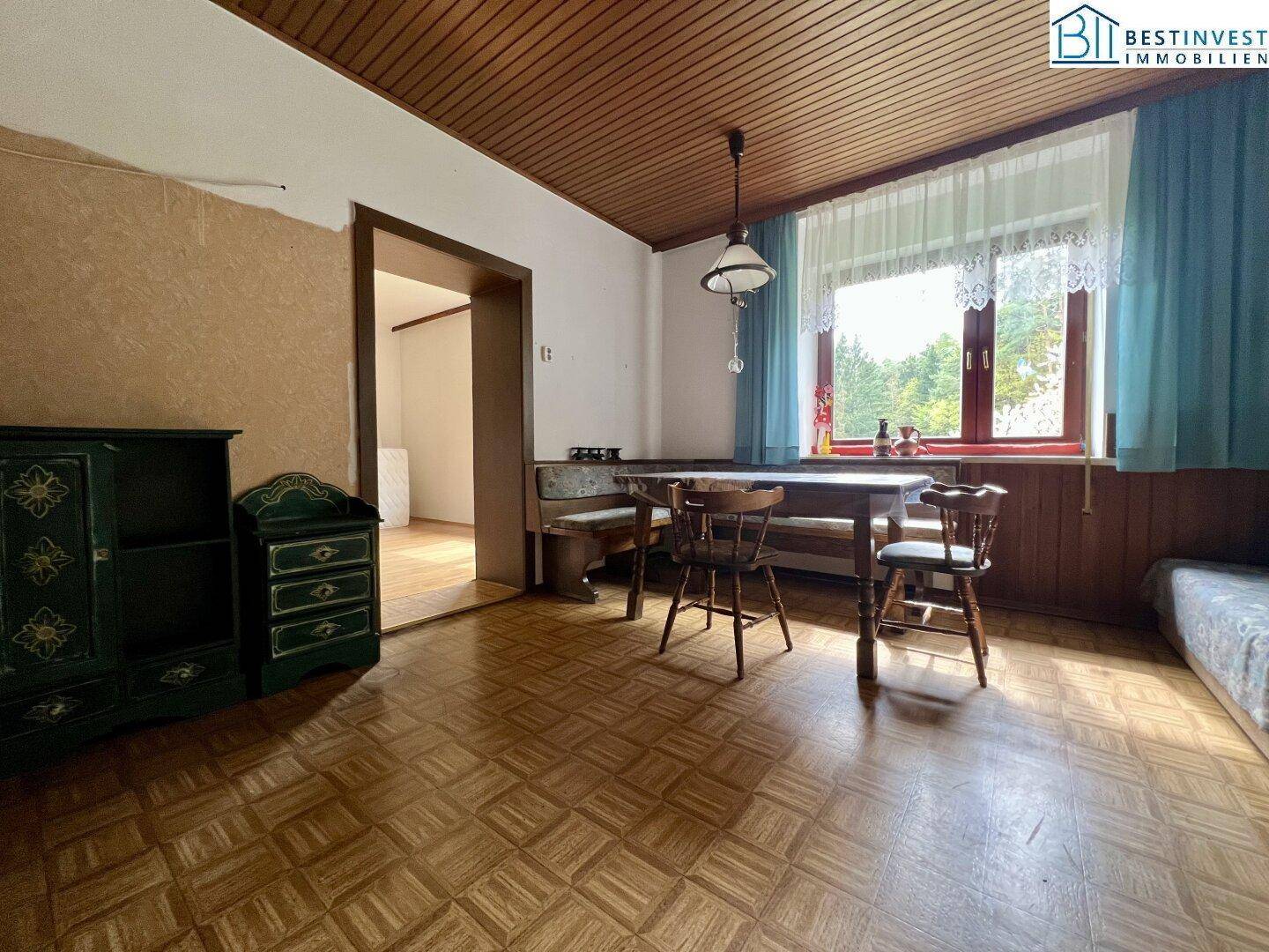 Rustikaler Essbereich mit Holzboden und Sitzbank, bietet einen Blick in ein angrenzendes Zimmer.
