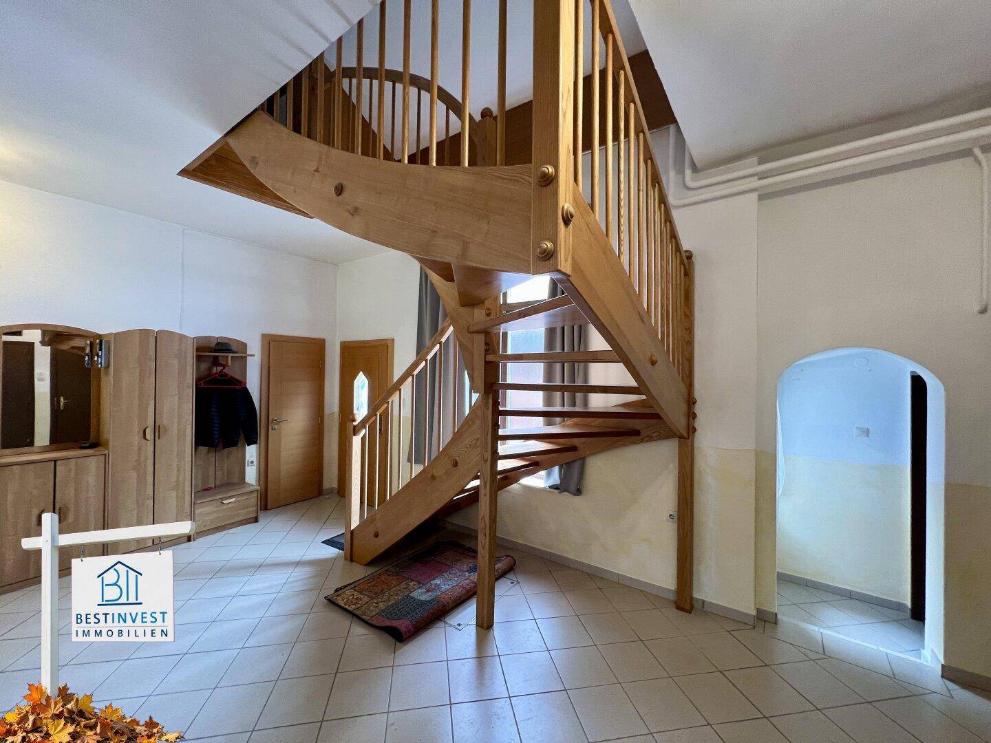 Geräumiger Flur mit einer geschwungenen Holztreppe und einem Garderobenschrank.