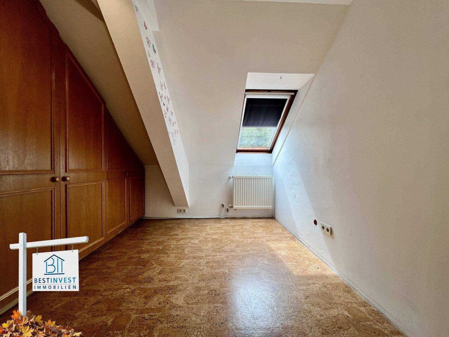 Schlafzimmer im Dachgeschoss mit Einbauschränken, Dachschrägen und einem Dachfenster.