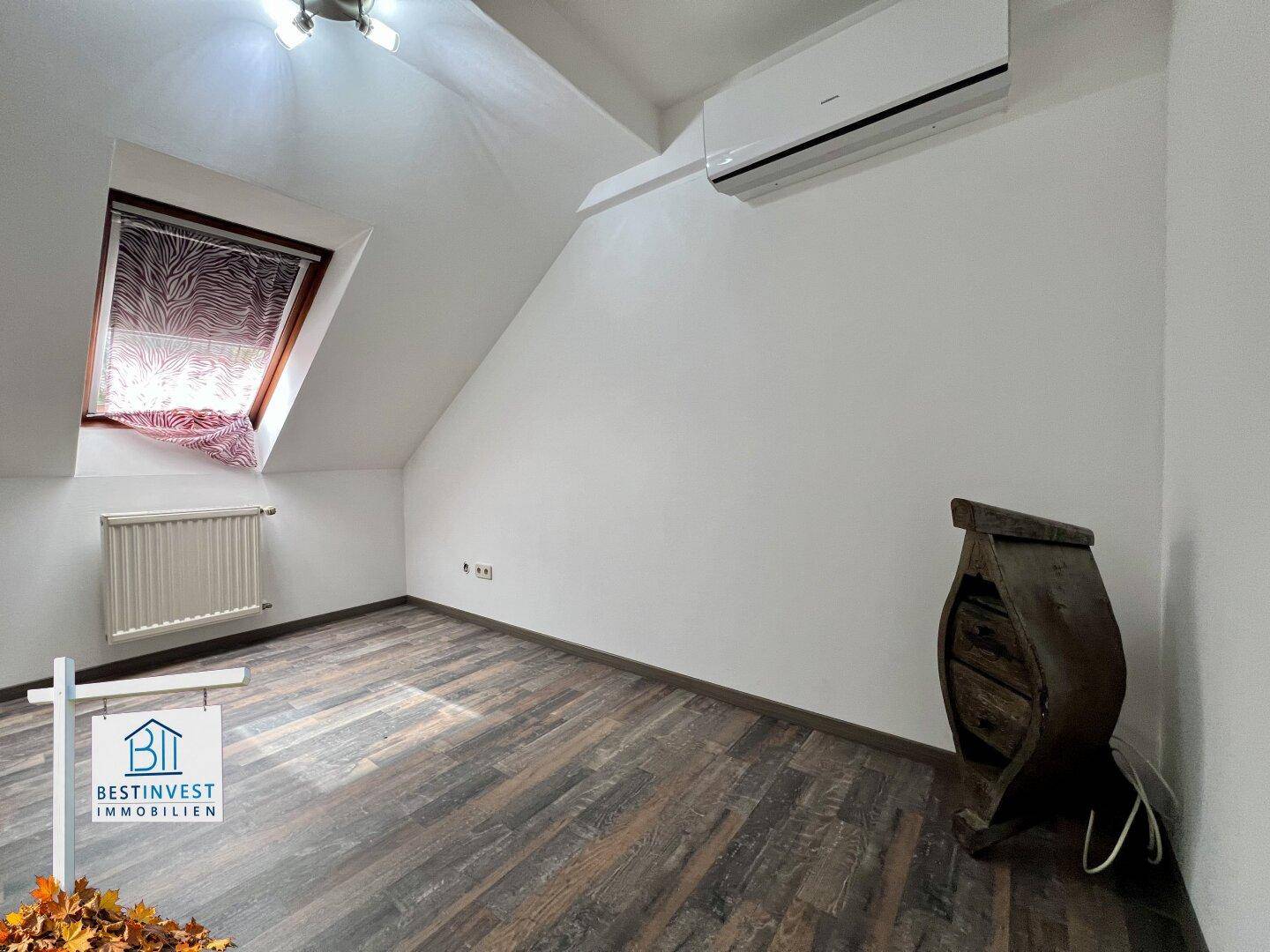 Helles Dachgeschosszimmer mit Dachschrägen, Dachfenster und installierter Klimaanlage.
