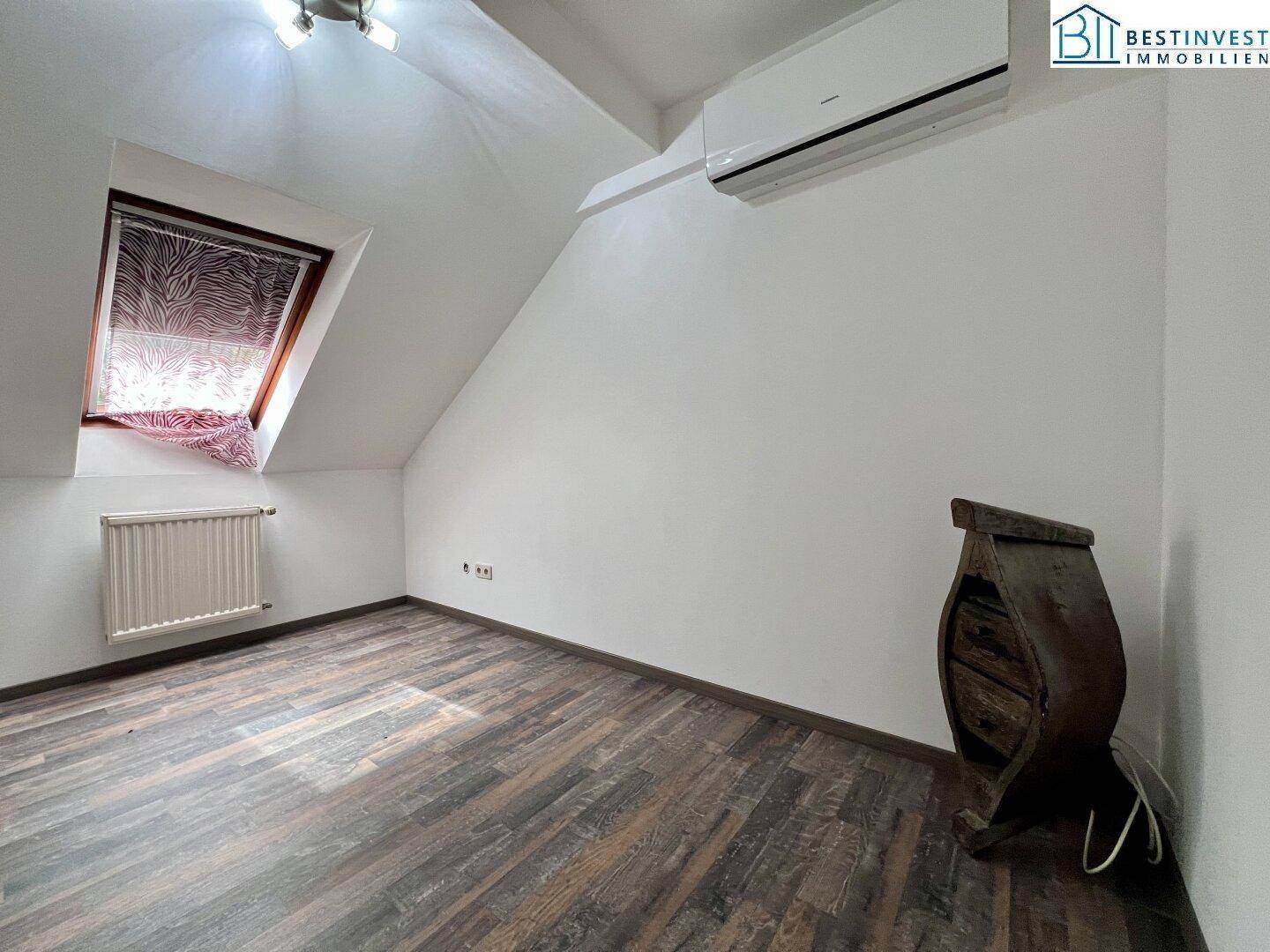 Helles Zimmer im Dachgeschoss mit Laminatboden und Klimaanlage, bietet angenehmes Raumklima.