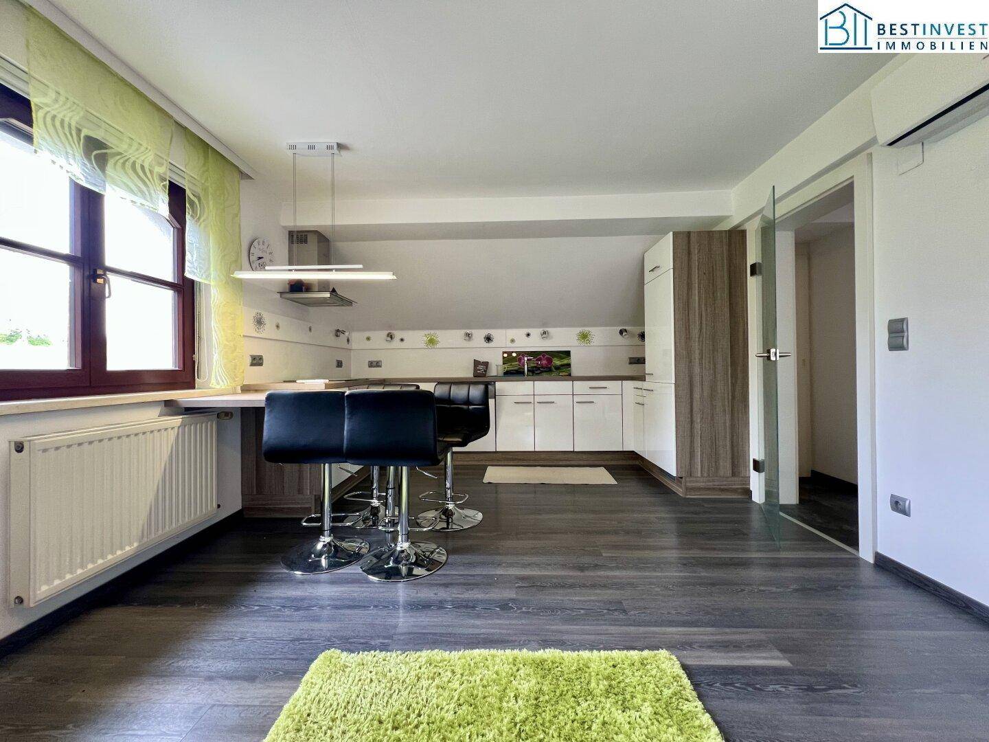 Moderne Küchenzeile im Dachgeschoss mit Barhockern und Laminatboden, ideal für offenes Wohnen.