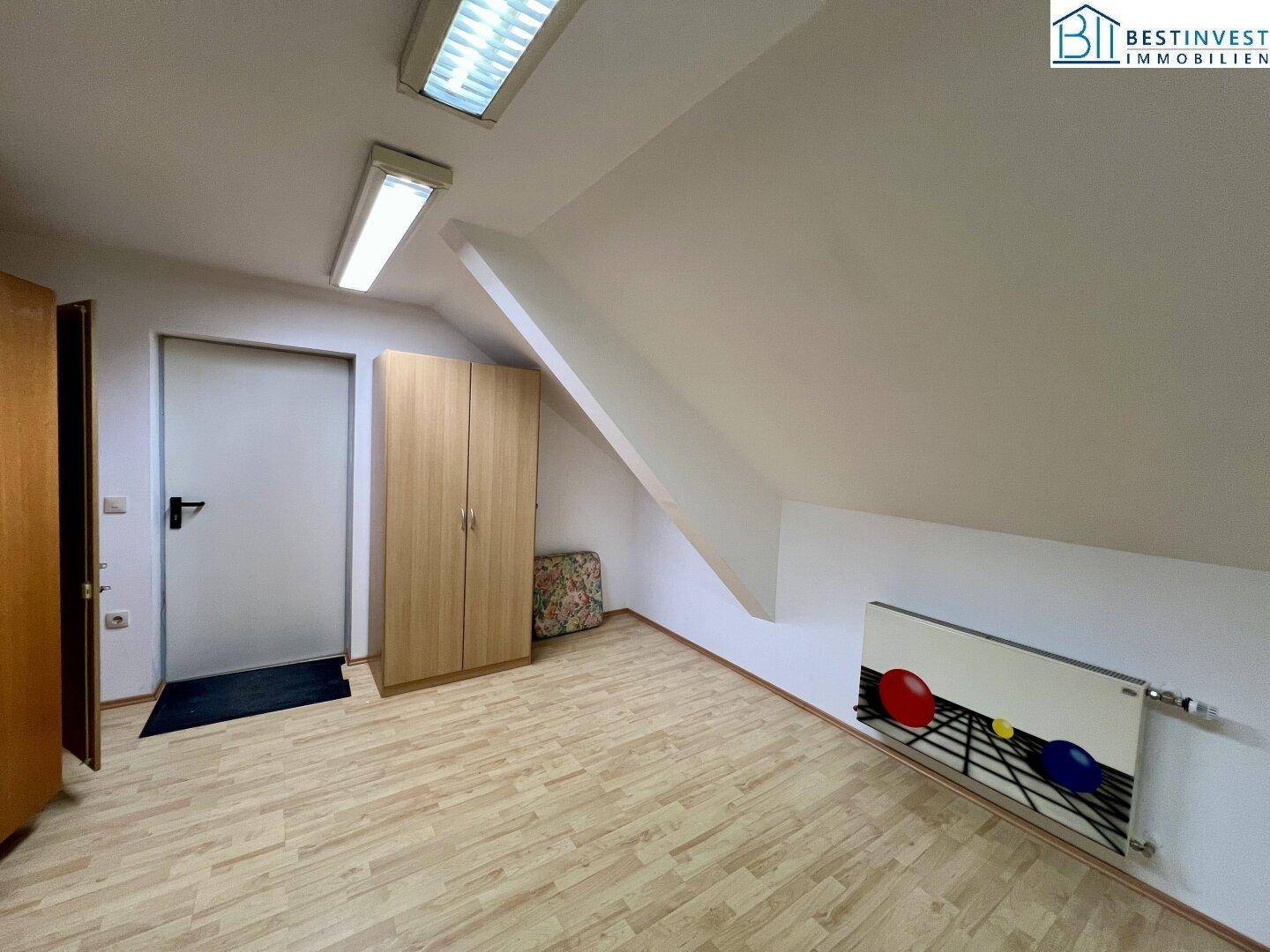 Geräumiges Zimmer im Dachgeschoss mit Dachschräge und Heizkörper, bietet vielseitige Nutzungsmöglichkeiten.