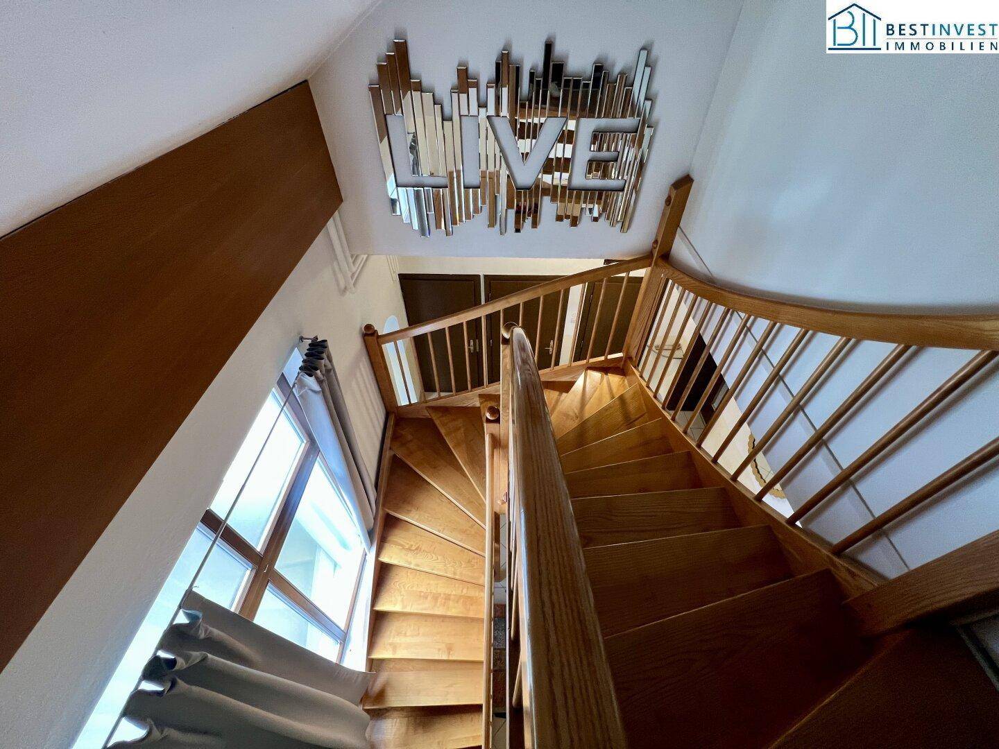 Elegante Holztreppe mit Geländer, die die verschiedenen Ebenen des Hauses miteinander verbindet.