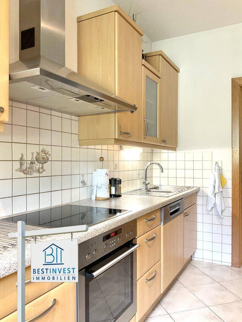 Gut ausgestattete Küche mit Holzfronten, modernen Geräten und Fliesenrückwand.