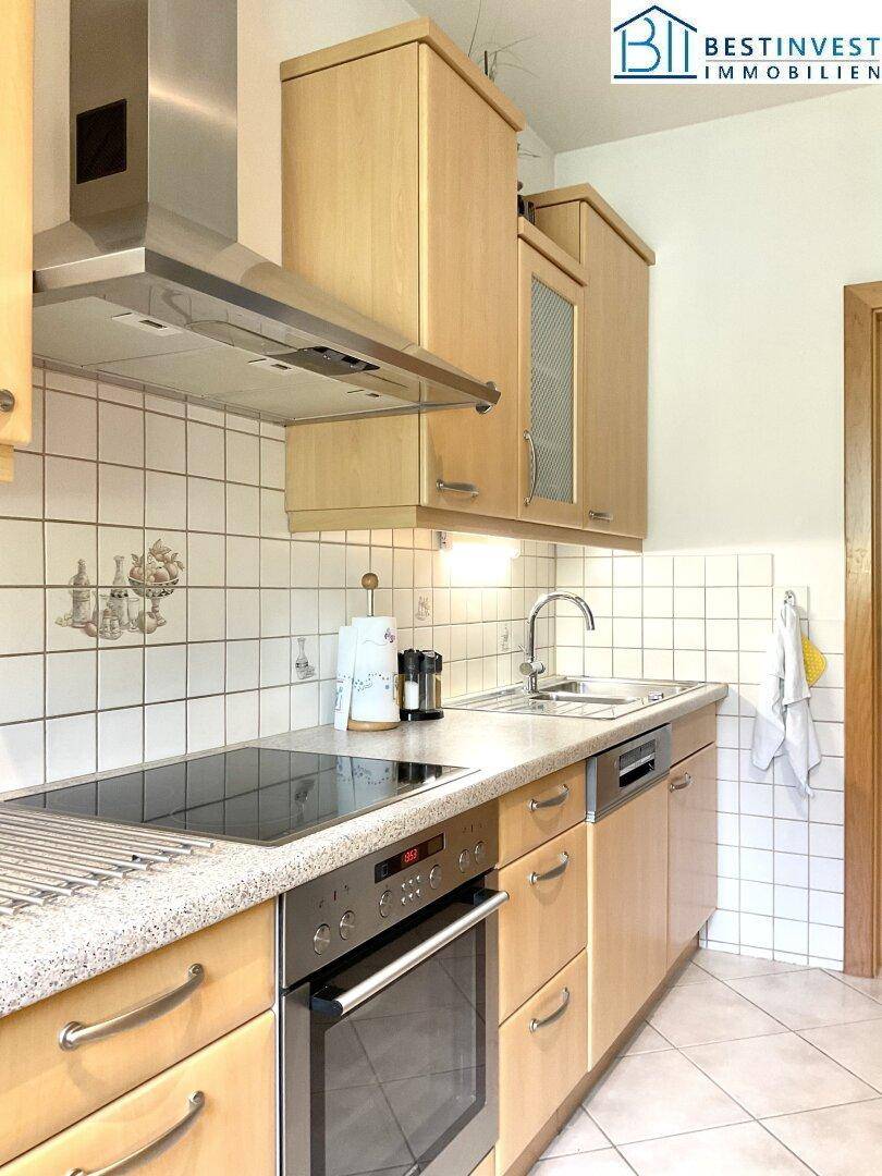 Gut ausgestattete Küche mit Holzfronten, Cerankochfeld, Backofen und Spüle, ideal für den täglichen Gebrauch.