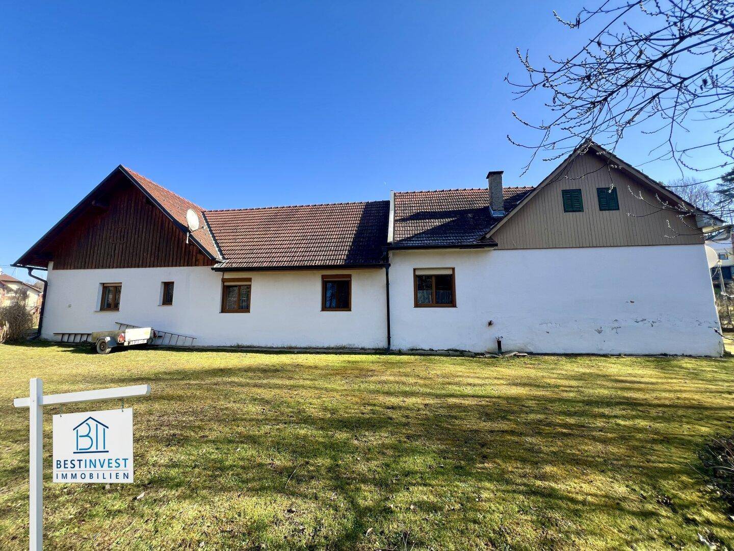 Weitläufige Ansicht des Hauses mit großem Garten und traditionellem Satteldach unter blauem Himmel.