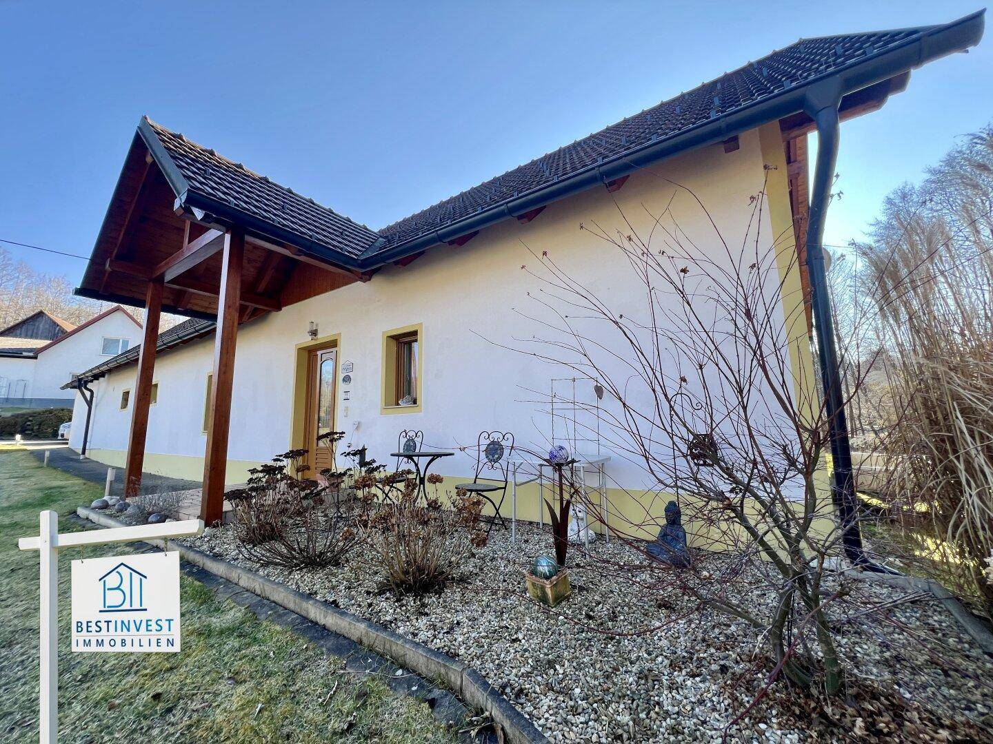 Eingangsbereich des Hauses mit kleiner Terrasse, Kiesbeet und schmiedeeisernen Gartenmöbeln.