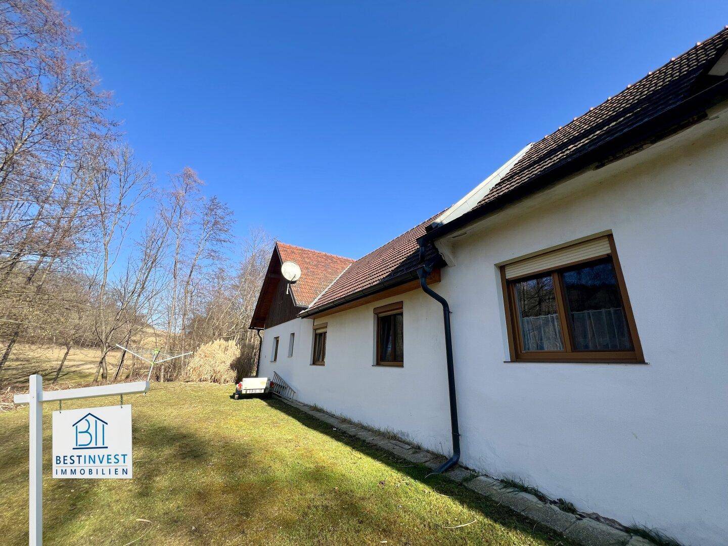 Seitenansicht des Hauses mit Rollläden an den Fenstern und weitem Blick in die grüne Umgebung.