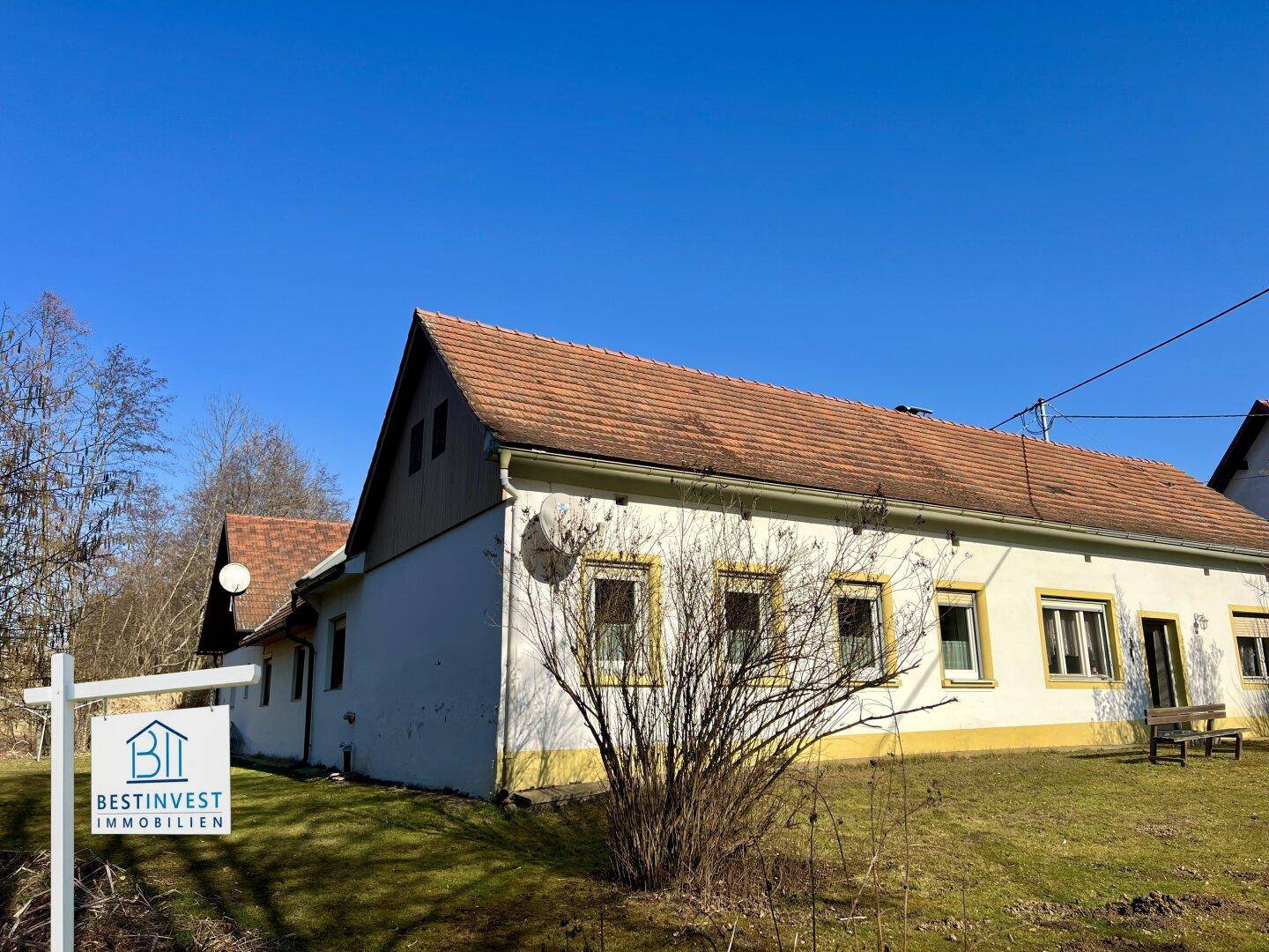 Längere Ansicht des Hauses mit mehreren Fenstern und einem gepflegten Rasenbereich im Vordergrund.