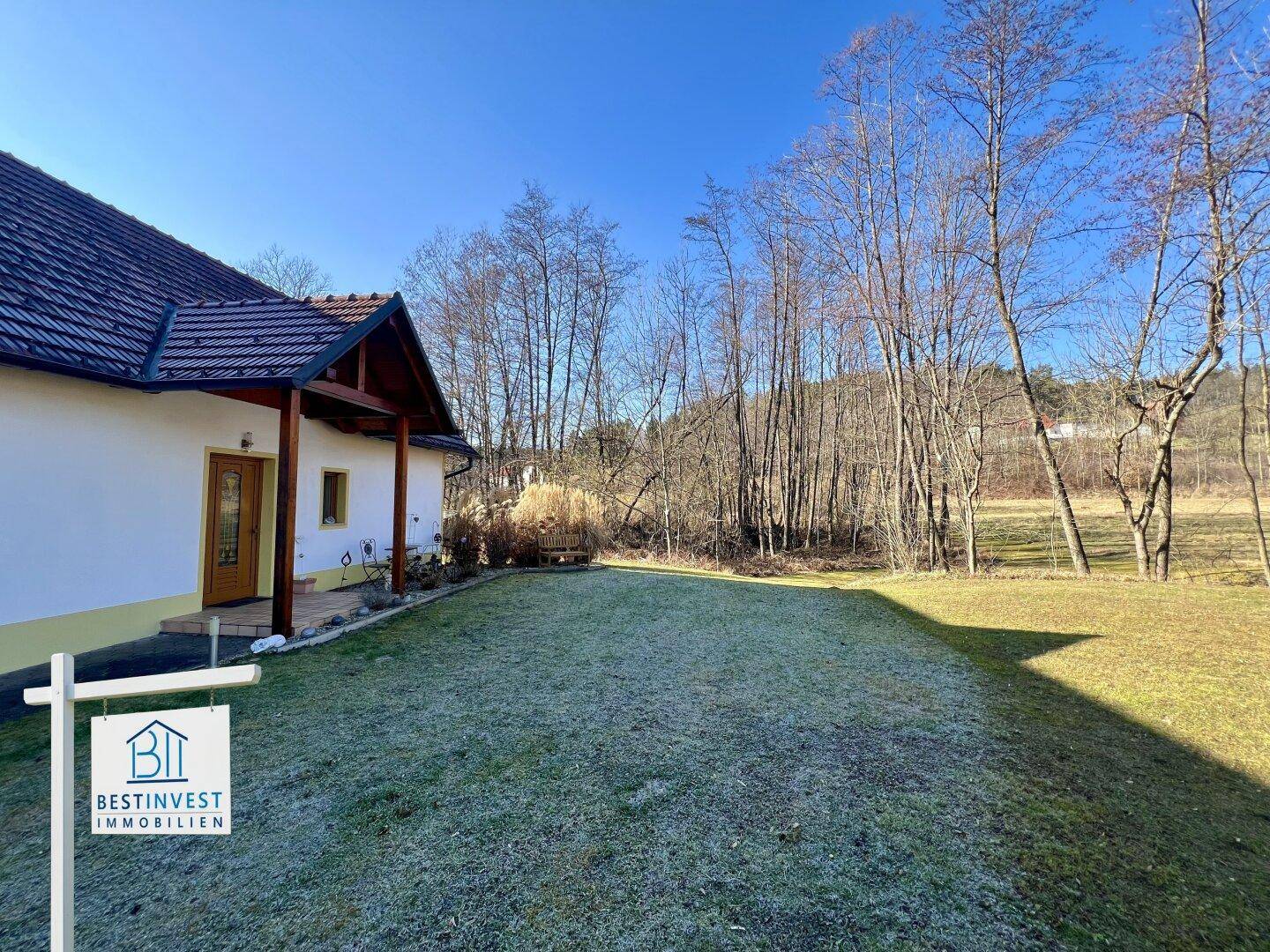 Weitläufiger Gartenbereich mit Rasenfläche und Blick auf die umgebende Natur und das Haus.