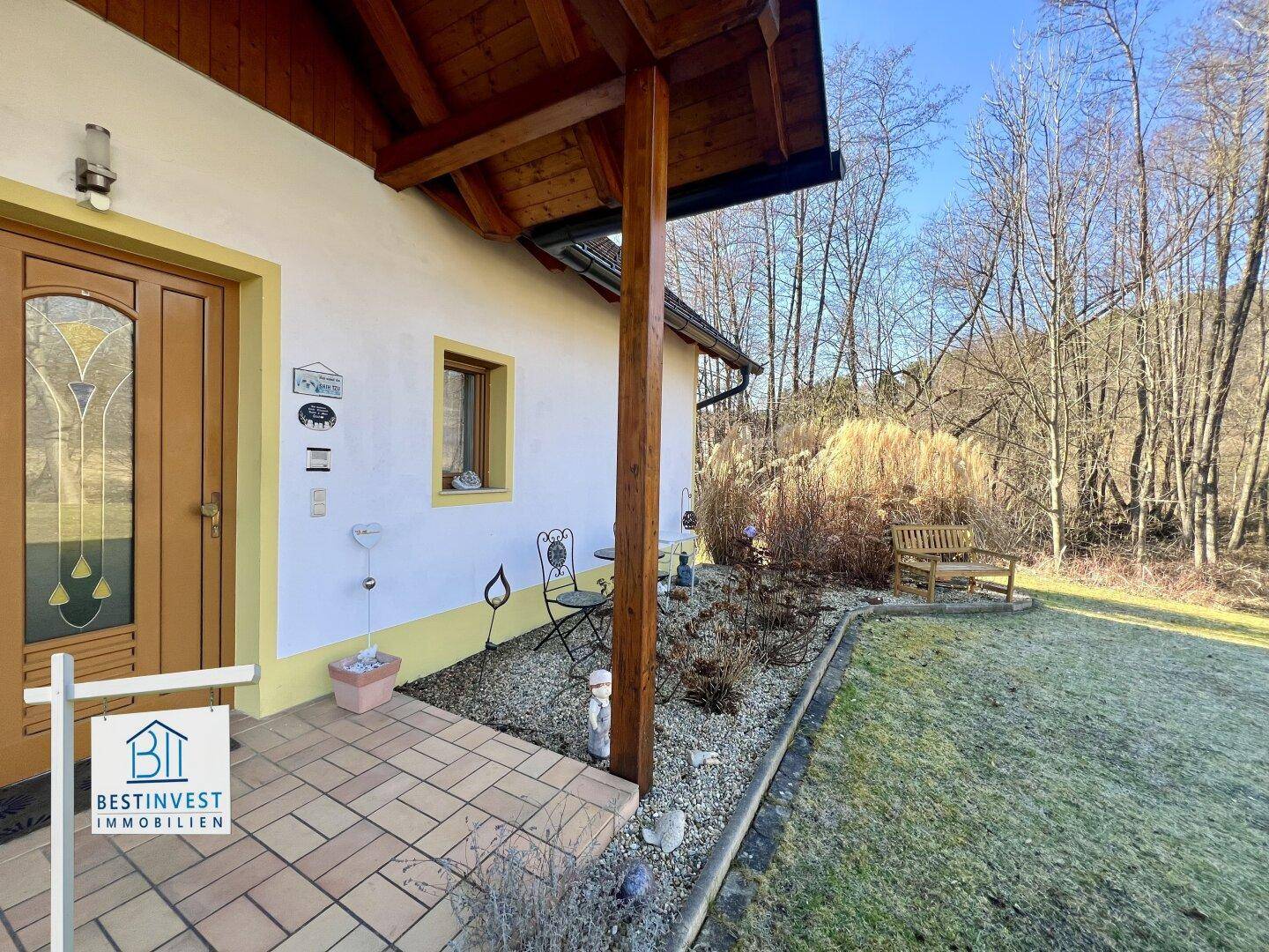 Eingangsbereich des Hauses mit gepflastertem Weg, kleinen Dekorationen und Blick in den Garten.
