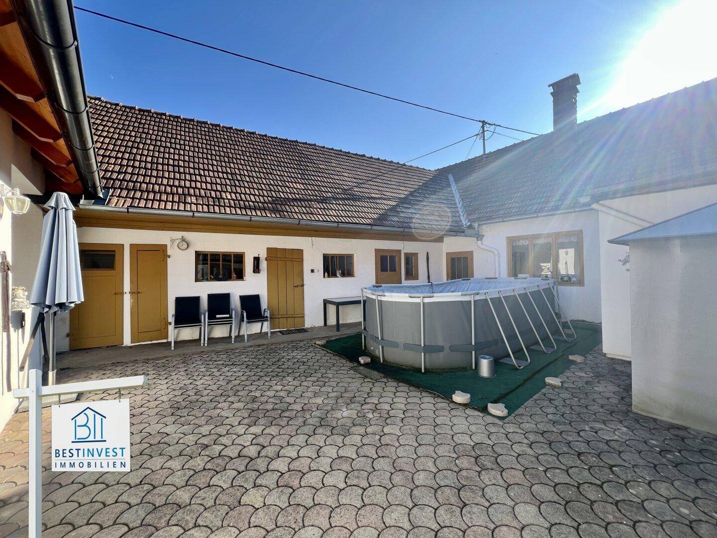 Gepflasterter Innenhof mit einem Aufstellpool, Gartenmöbeln und einem kleinen Pavillon.