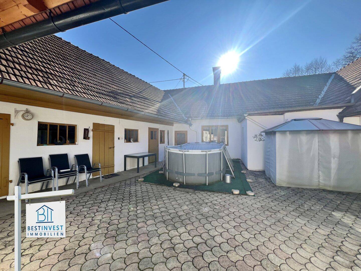 Sonniger Innenhof mit Aufstellpool, Sitzgelegenheiten und einem kleinen Gartenpavillon.