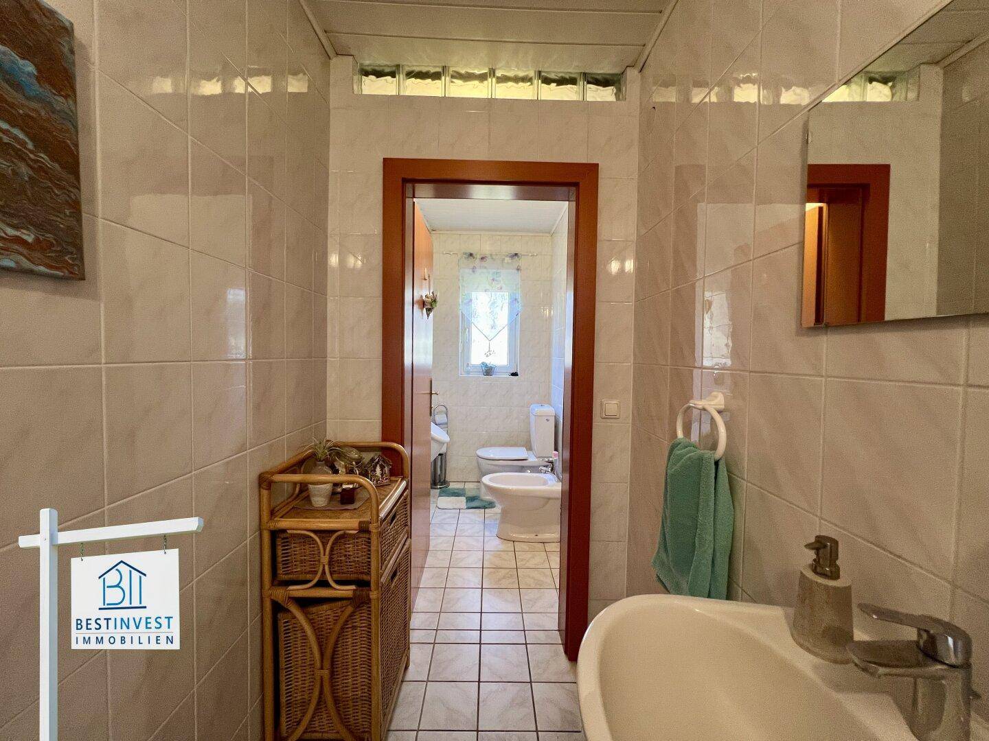Gefliestes Badezimmer mit Waschbecken, Bidet und WC, in einem traditionellen Stil gehalten.