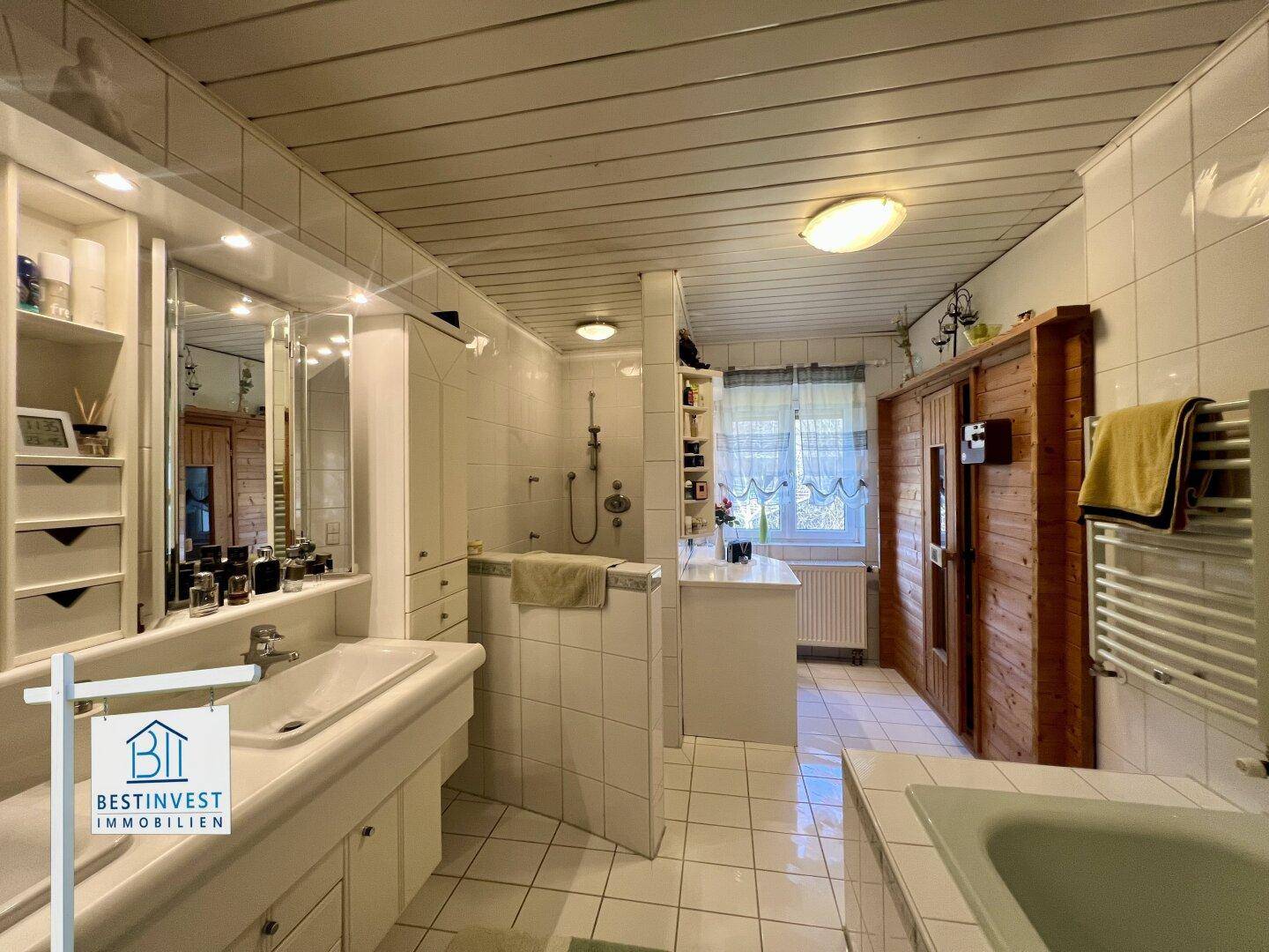 Helles Badezimmer mit integrierter Sauna, Dusche und großem Waschtisch unter Holzdecke.