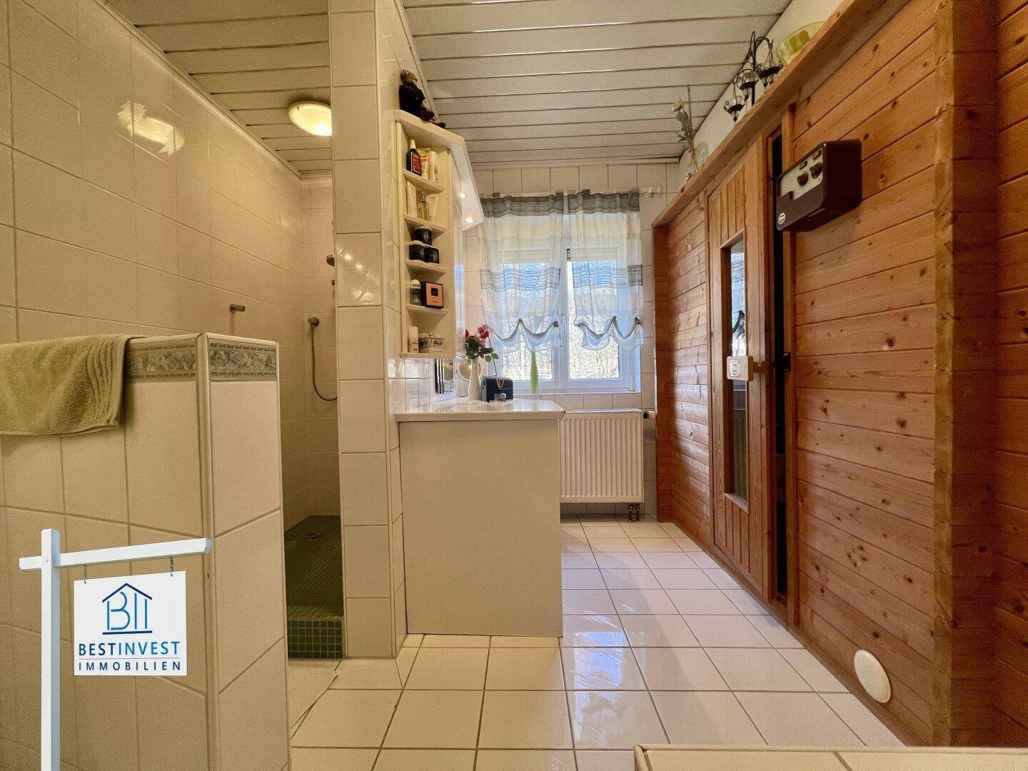 Modernes Badezimmer mit begehbarer Dusche und einer Holzkabine, die eine Sauna beherbergt.