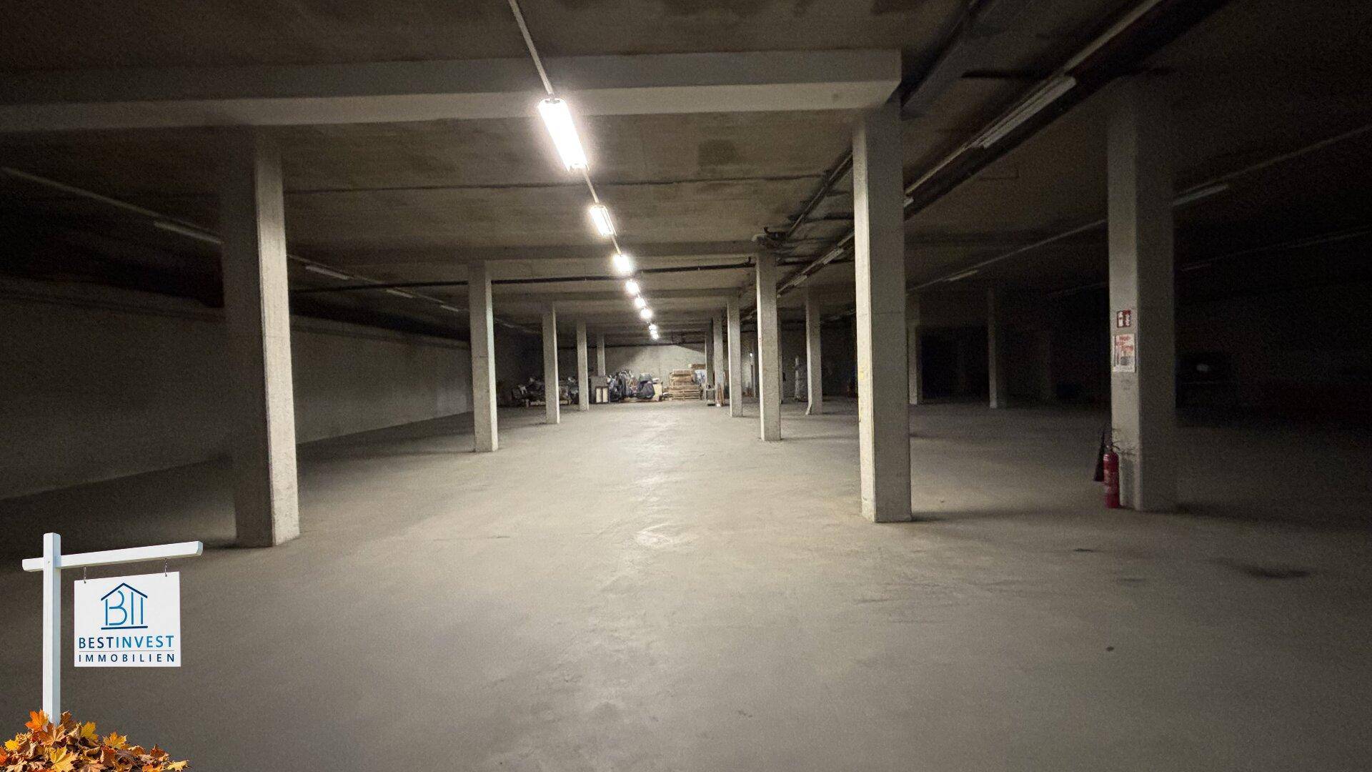 Geräumige Tiefgarage mit Betonpfeilern und Reihen von Deckenleuchten.