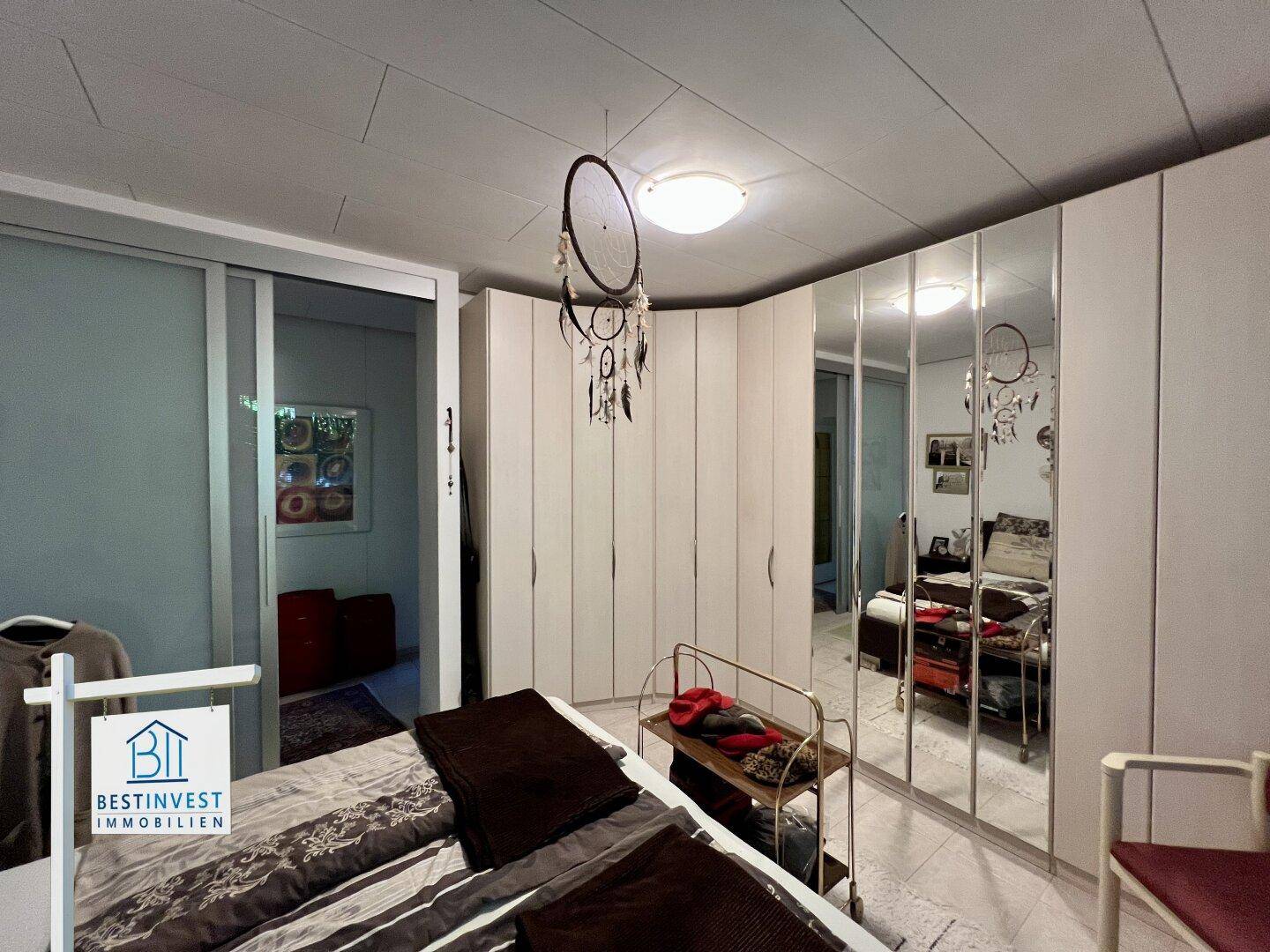Schlafzimmer mit Spiegelschränken, Doppelbett und schlichter Einrichtung, bietet viel Stauraum.