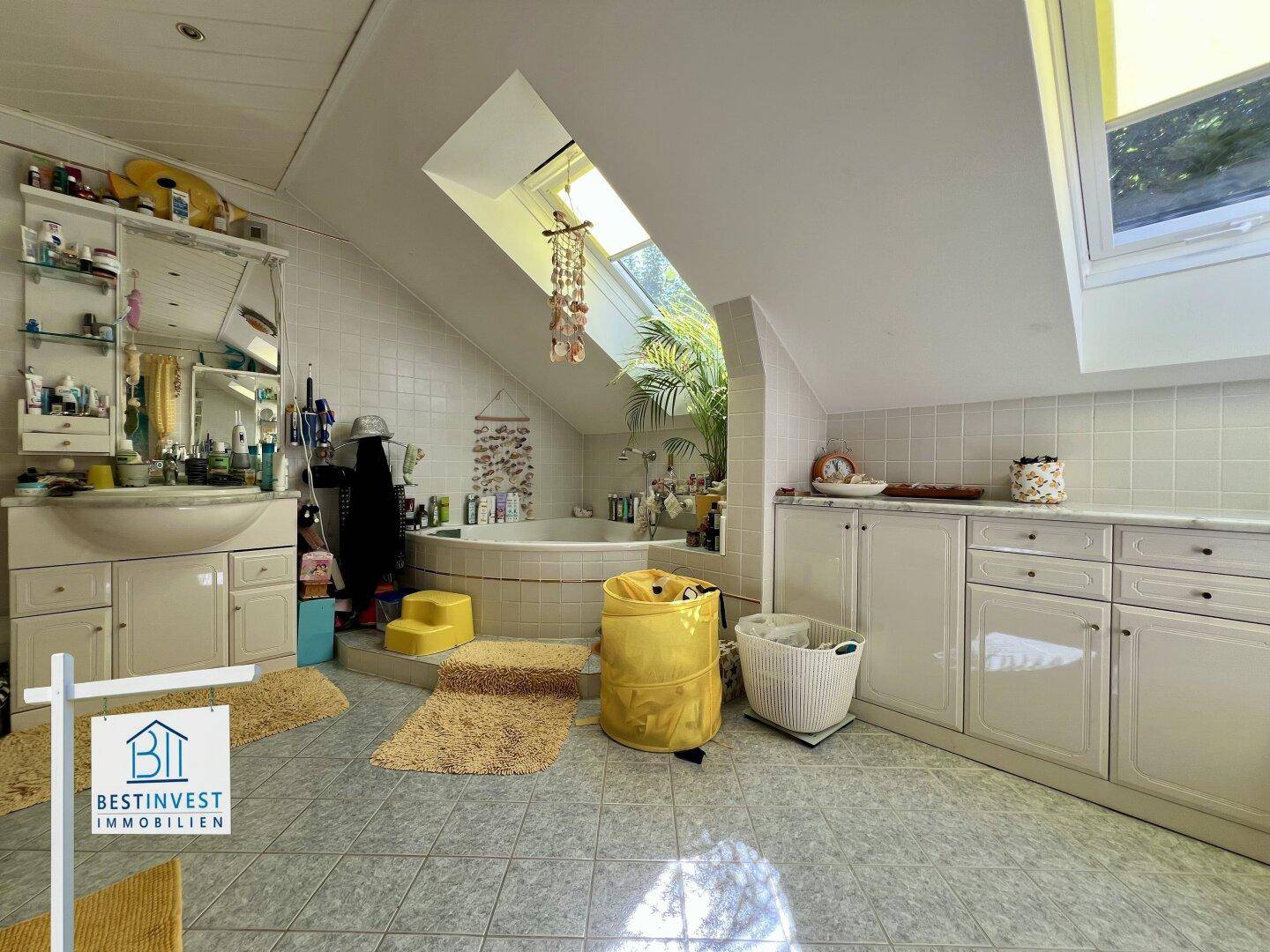 Geräumiges Badezimmer mit Eckbadewanne, Dachfenstern und Doppelwaschbecken unter schrägen Decken.
