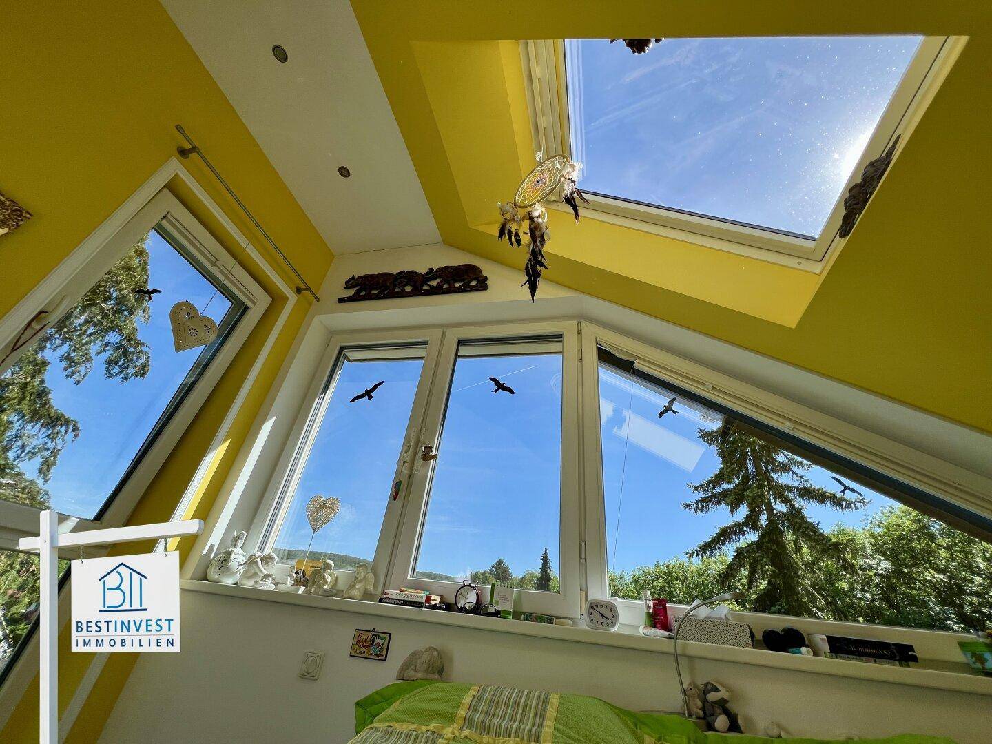 Helles Dachgeschosszimmer mit großen Fenstern und Dachschrägen, bietet weite Ausblicke.