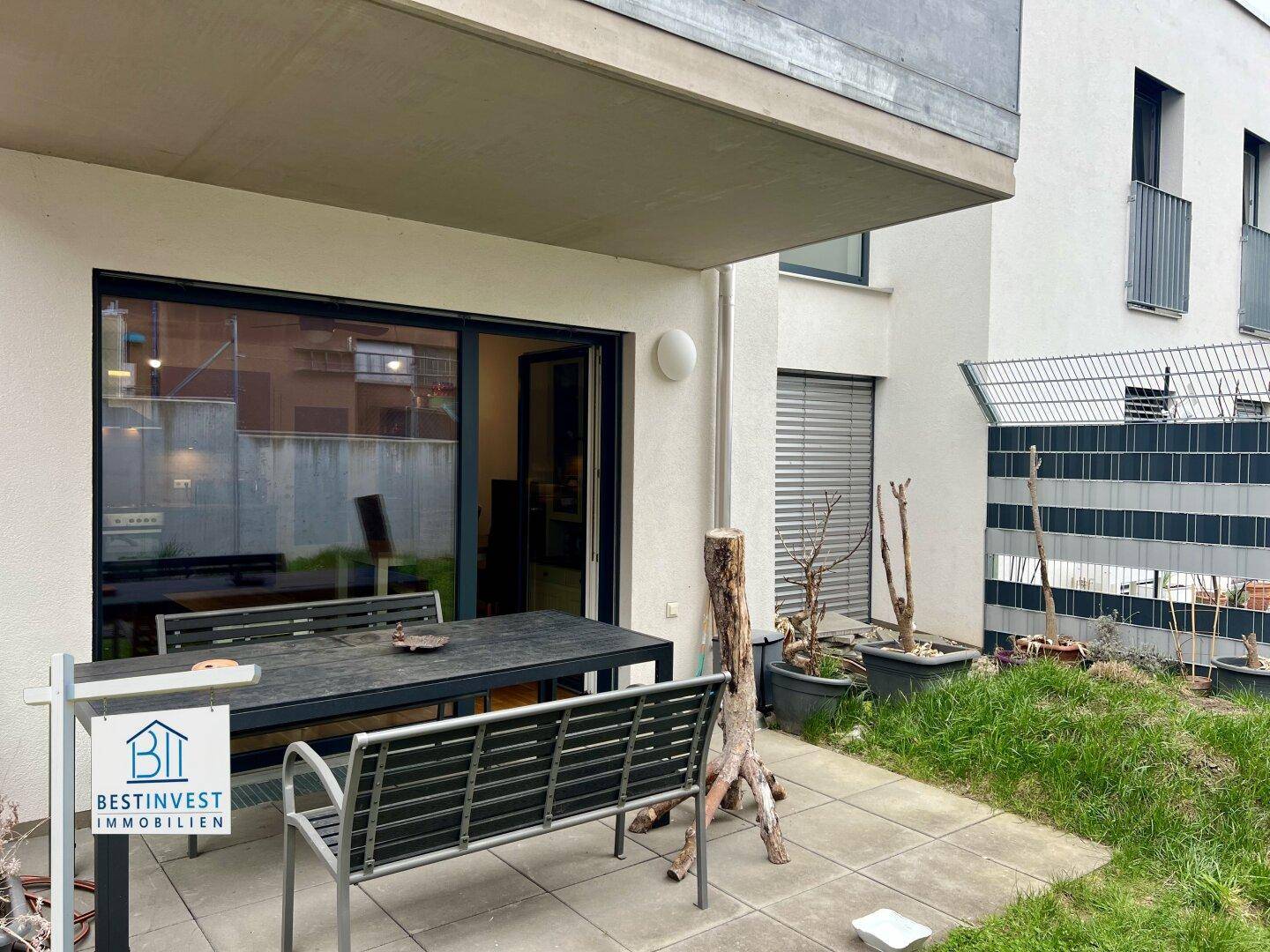 Terrasse mit Gartenmöbeln und Zugang zum kleinen Gartenbereich.