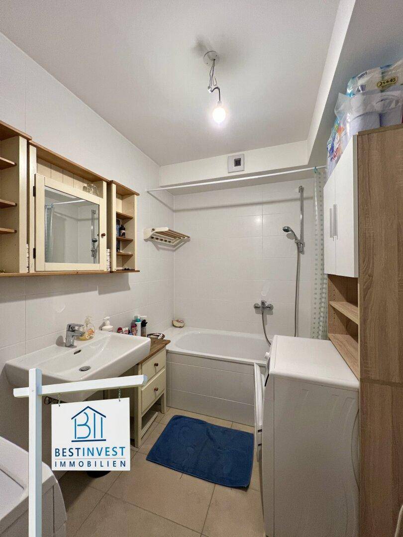 Helles Badezimmer mit Badewanne, Waschbecken und weißen Wandfliesen.