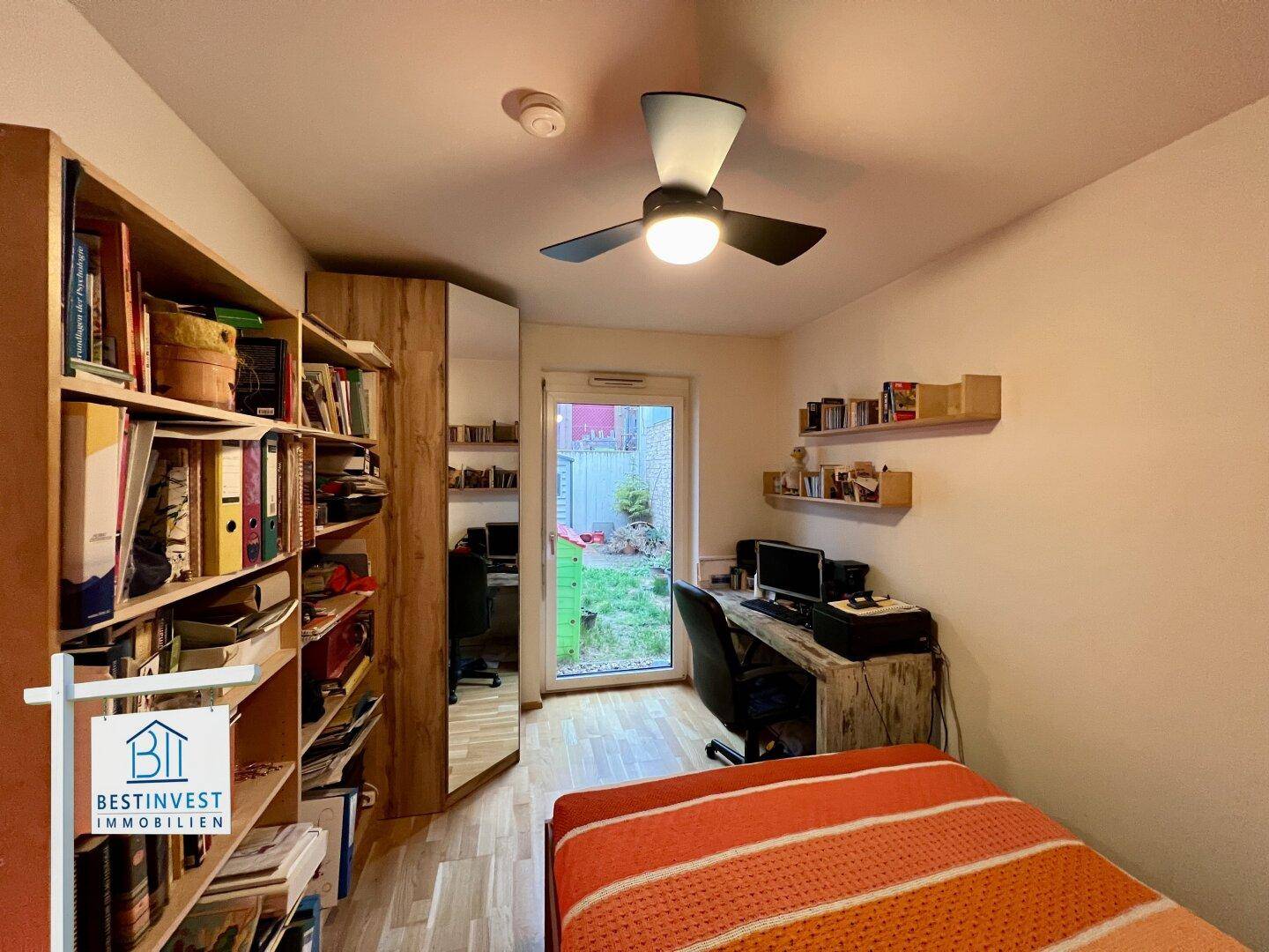 Schlafzimmer mit Holzboden, Deckenventilator und Zugang zum Garten.