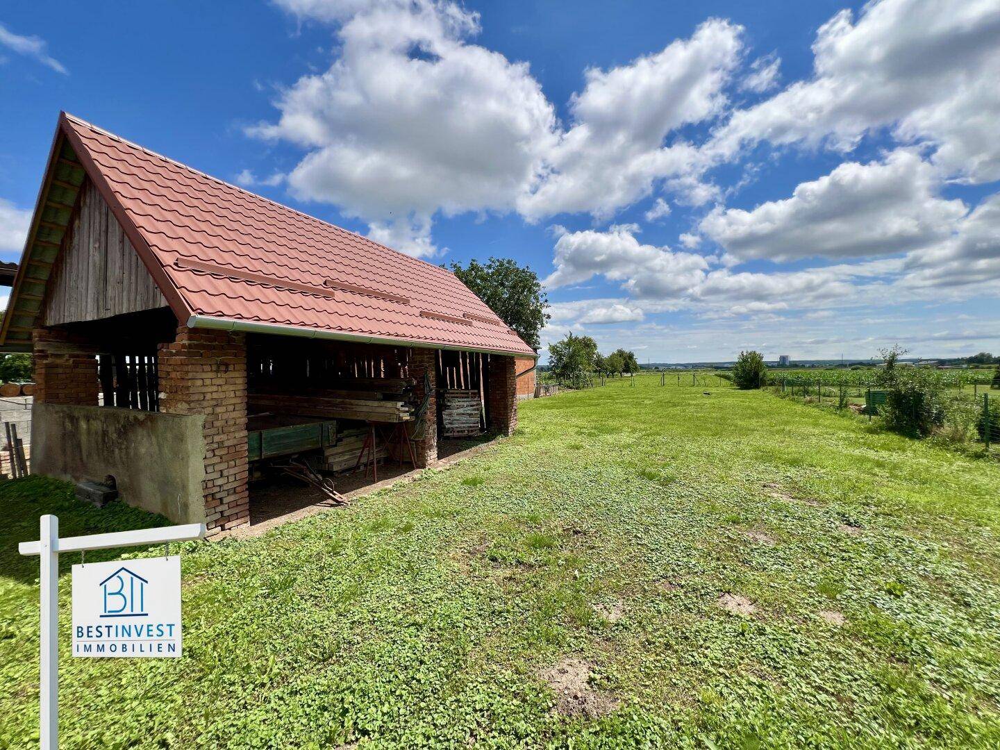 Kleines Nebengebäude auf einer weiten grünen Wiese mit Blick auf die umliegende Landschaft.